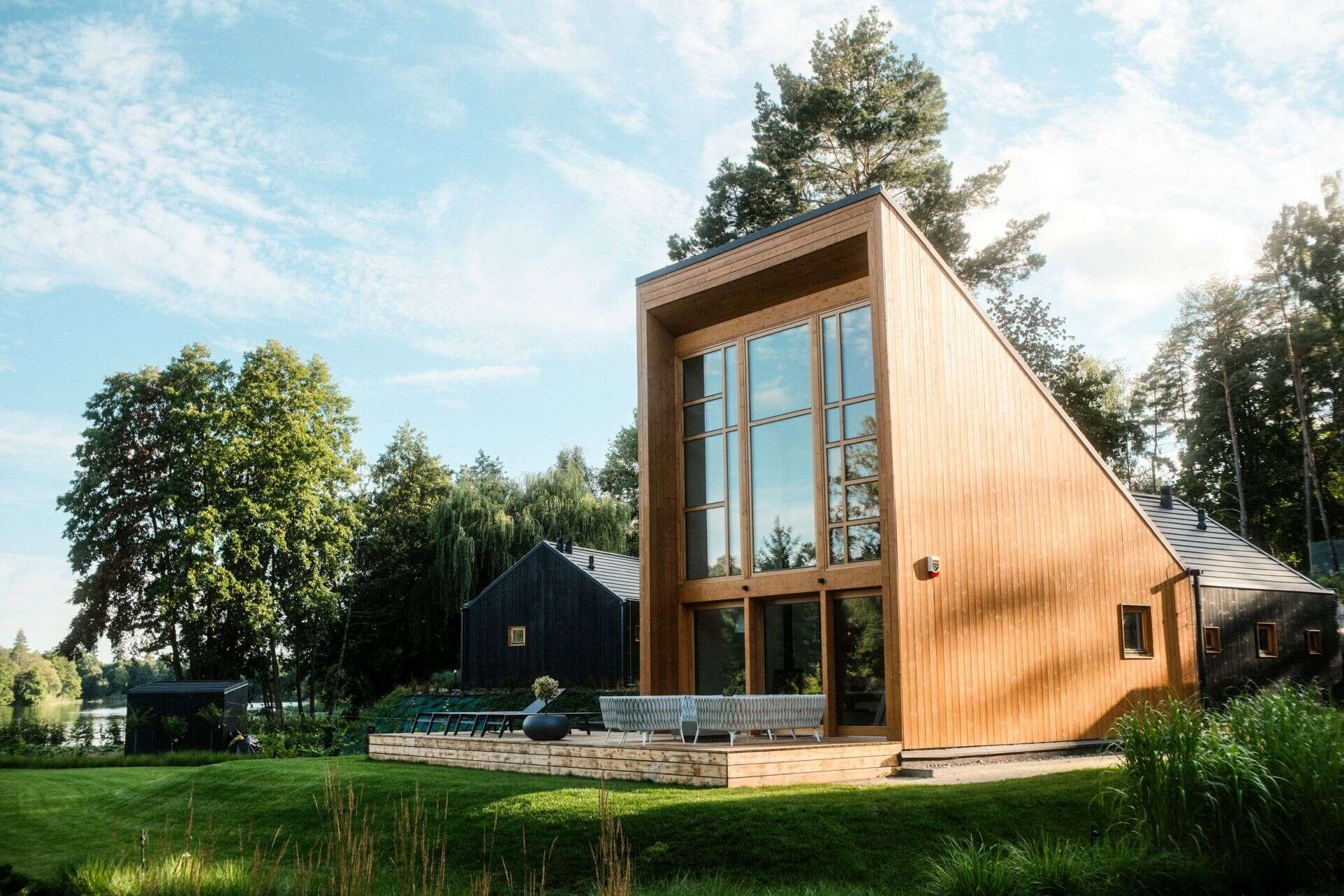 Explore the contemporary architecture of Kalbornia Mazury, featuring light wooden facades, dark private volumes and expansive glazing that opens the homes towards the Polish lake and forest.