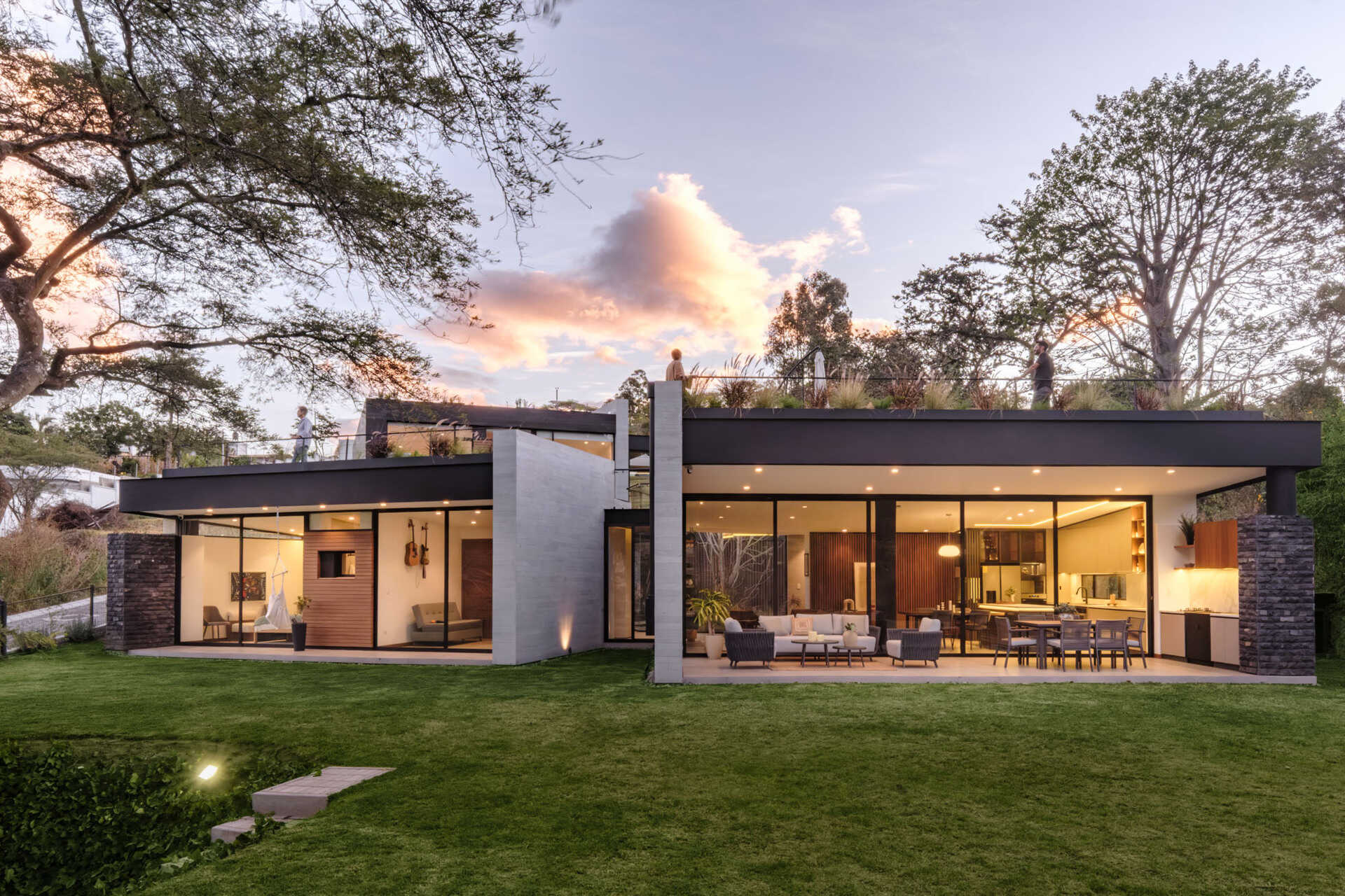 Explore a contemporary house in Puembo, Ecuador, with angular architecture, grass-covered roof terraces, a planted central courtyard, and sheltered outdoor living spaces. Designed by A1 Arquitectura Avanzada, the home combines pale walls, dark roof edges, wood-toned panels, and expansive glazing.