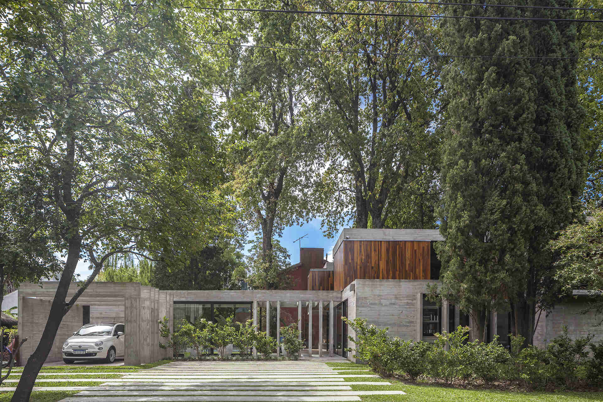Casa Aranzazu in Buenos Aires by Besonias Almeida arquitectos is a modern concrete and wood house designed around mature trees, with large windows and a leafy corner-lot setting.