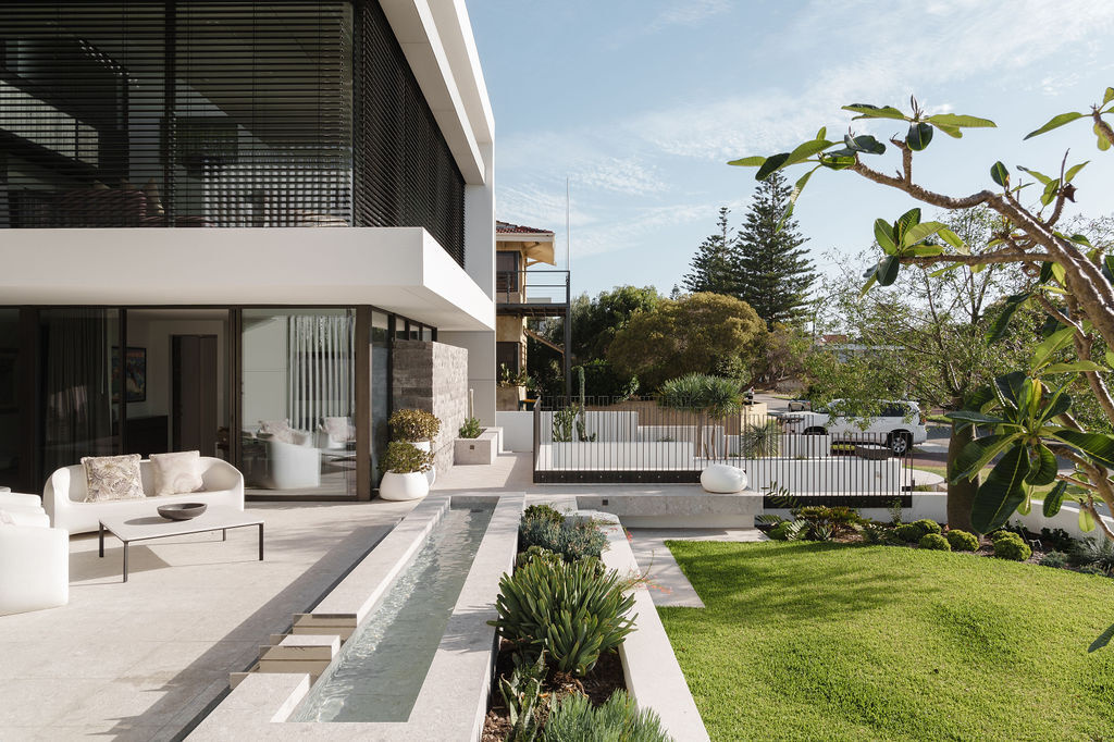 The front patio and water feature at Mezzanine House combine concrete, timber, landscaping and water in a contemporary Perth home designed by Craig Steere Architects.