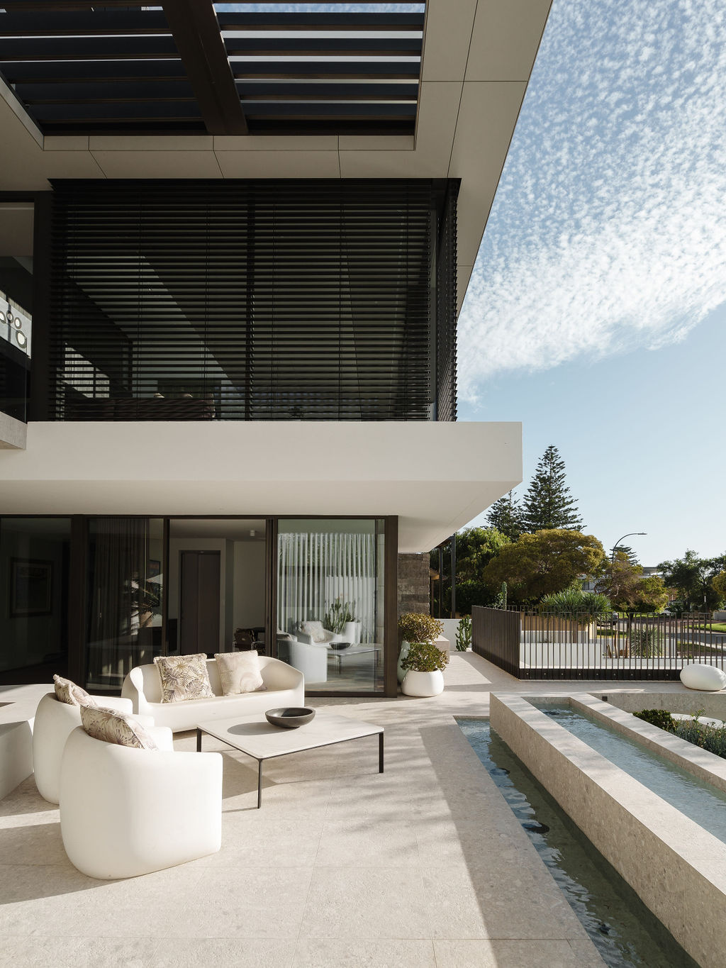 The front patio and water feature at Mezzanine House combine concrete, timber, landscaping and water in a contemporary Perth home designed by Craig Steere Architects.