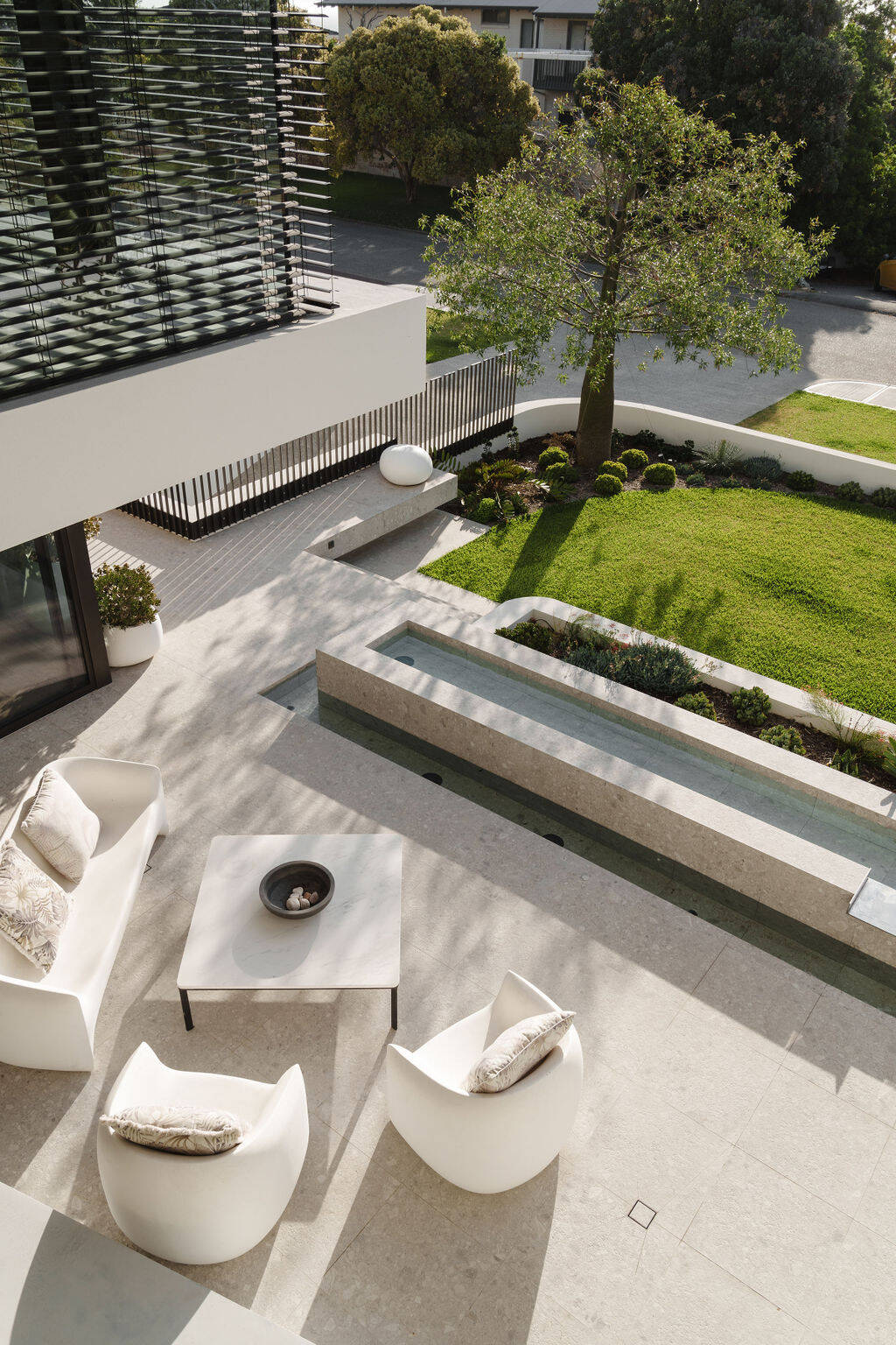 The front patio and water feature at Mezzanine House combine concrete, timber, landscaping and water in a contemporary Perth home designed by Craig Steere Architects.