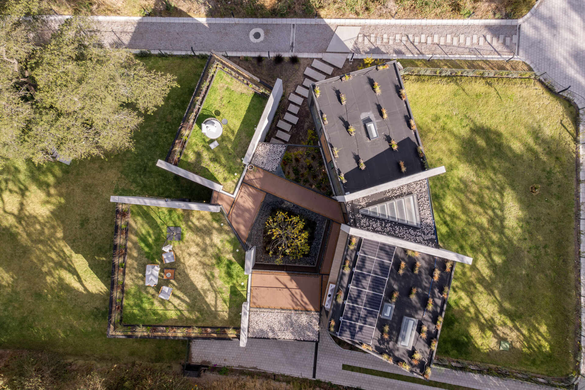 Explore a contemporary house in Puembo, Ecuador, with angular architecture, grass-covered roof terraces, a planted central courtyard, and sheltered outdoor living spaces. Designed by A1 Arquitectura Avanzada, the home combines pale walls, dark roof edges, wood-toned panels, and expansive glazing.