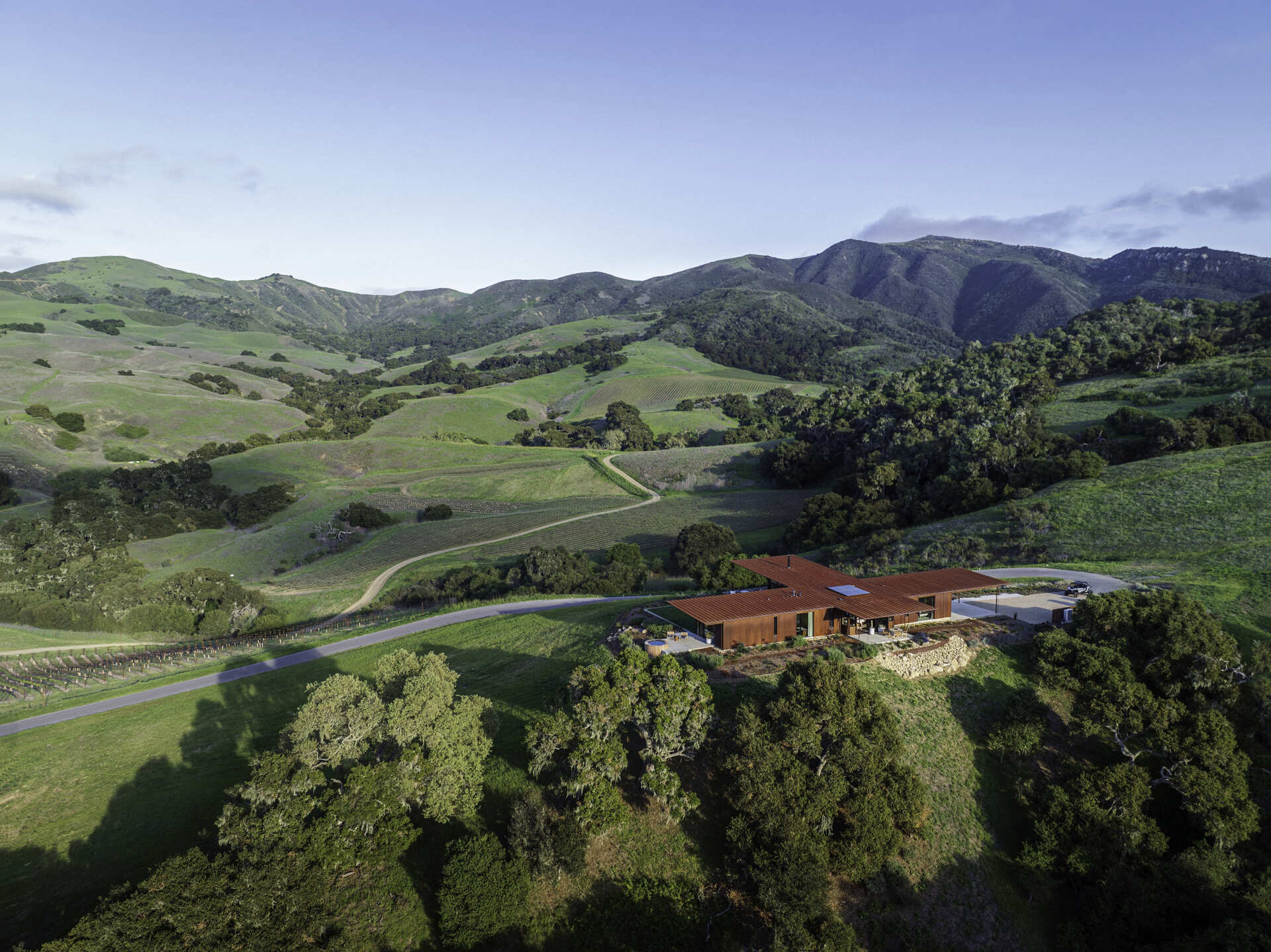 Explore the compact T-shaped plan of Vineyard Residence by Clayton Korte, with private bedroom suites surrounding a central kitchen and living area and outdoor spaces extending at both ends.