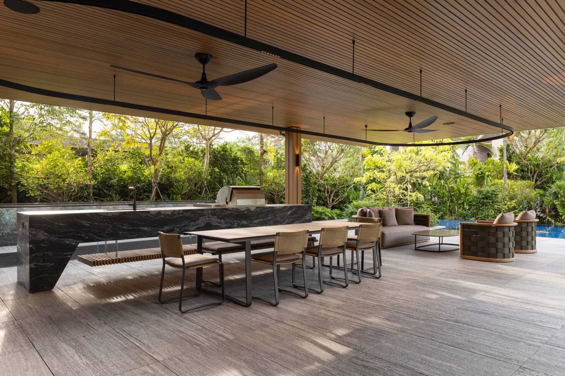 A modern house open to the outdoors with a covered outdoor living room and swimming pool.