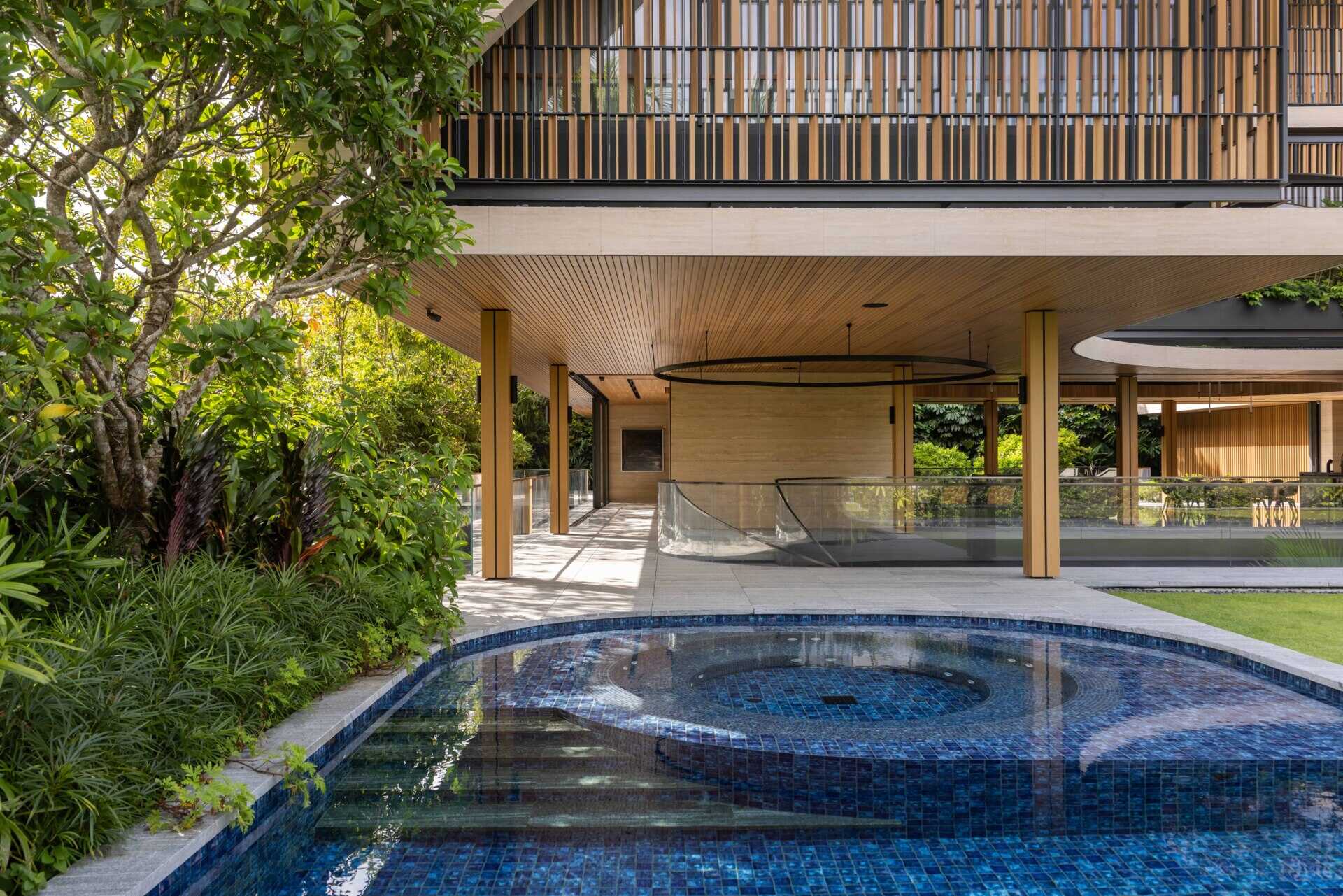 A modern house open to the outdoors with a covered outdoor living room and swimming pool.