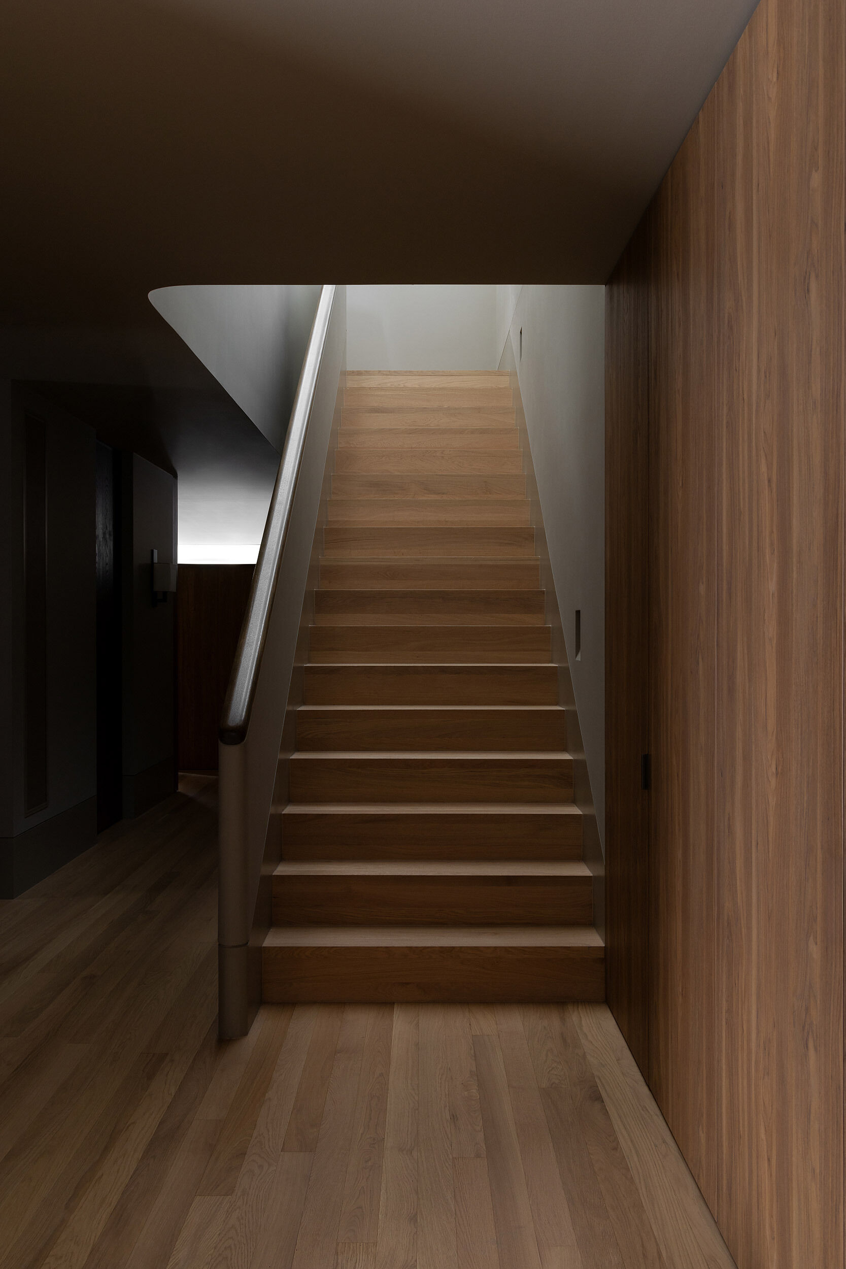 A softly detailed staircase beneath a skylight connects Casa Piva’s ground floor with the private rooms above, while drawing natural light into the darker entry area below.