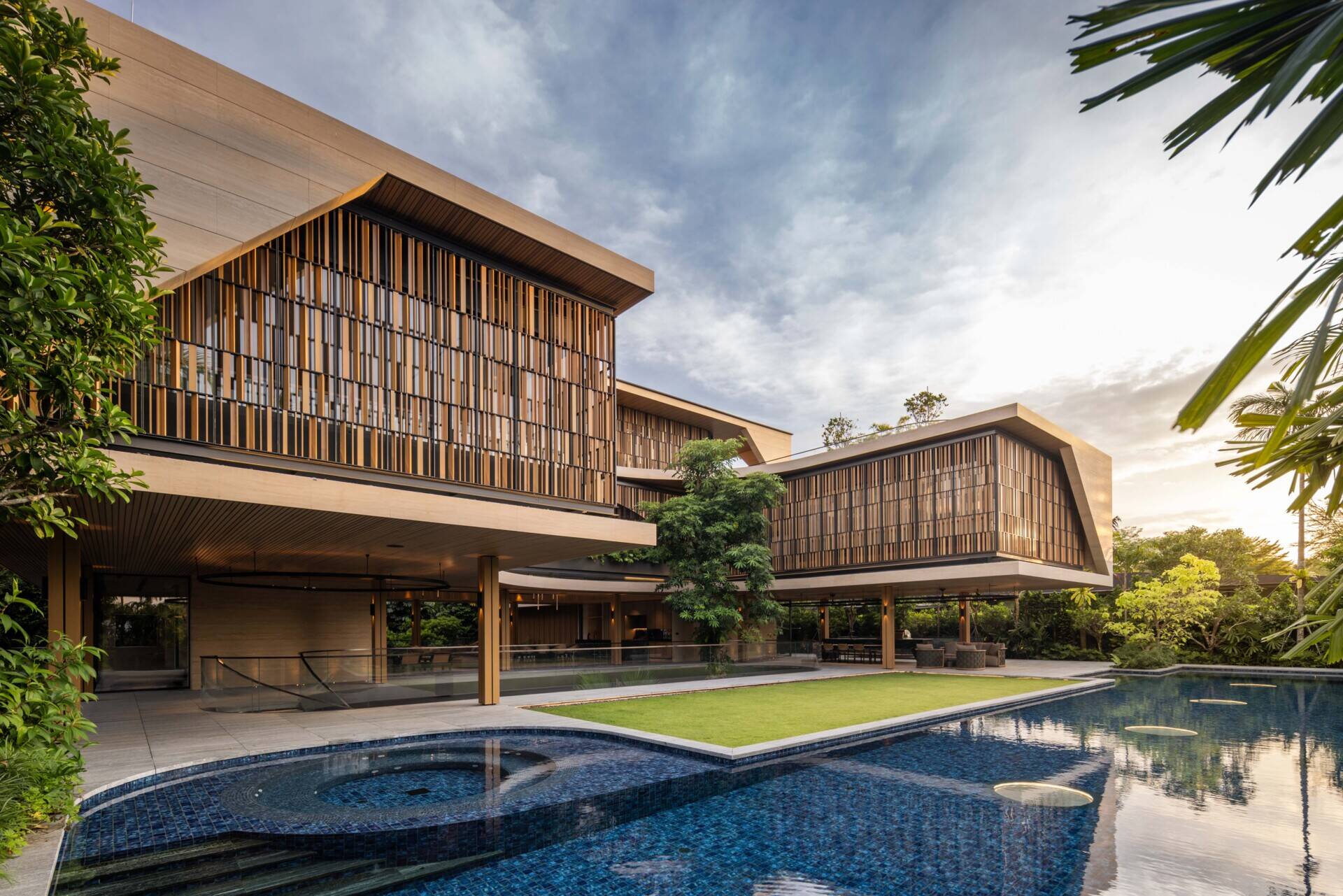 A delicate screen wraps the upper bedrooms, filtering sunlight and neighbouring views while preserving views of the greenery.