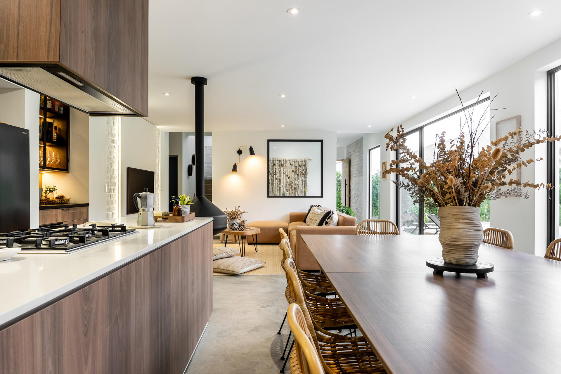 Casa Berna’s open kitchen has timber cabinetry, a white countertop and a gas cooktop, with a warmly lit bar tucked into a nearby recess.