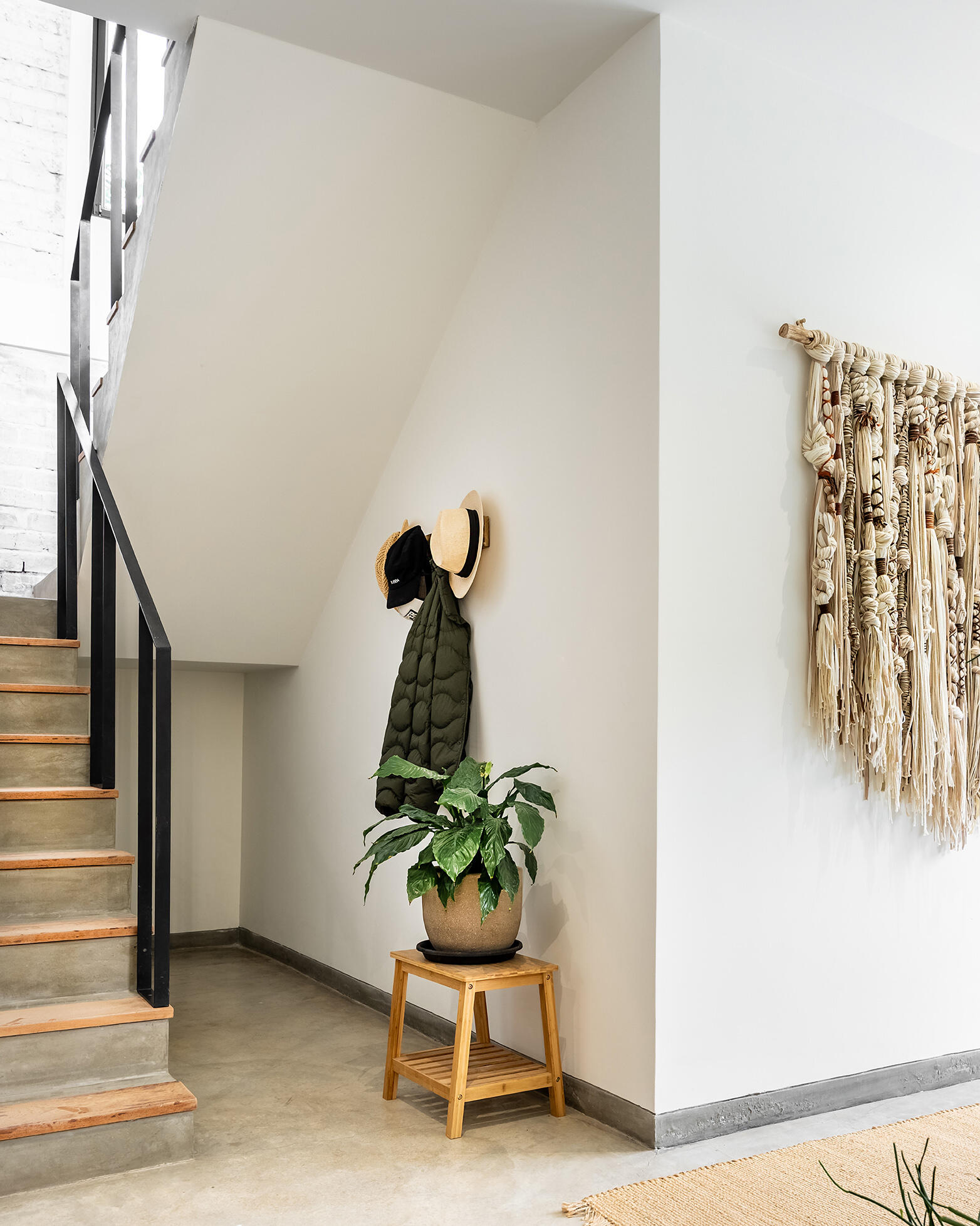 A black metal handrail and timber-edged concrete steps define the staircase at Casa Berna, visible through an internal window beside the entry.