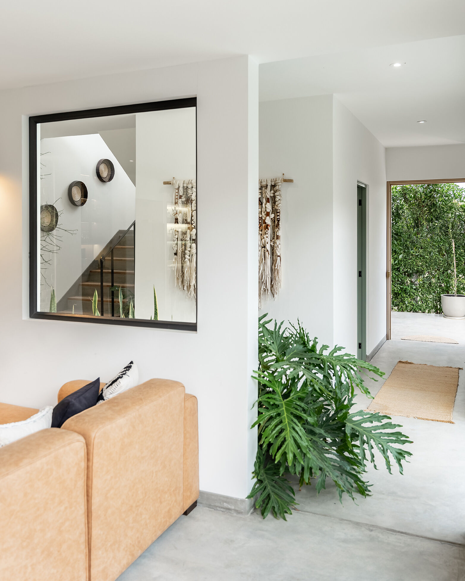 A black metal handrail and timber-edged concrete steps define the staircase at Casa Berna, visible through an internal window beside the entry.