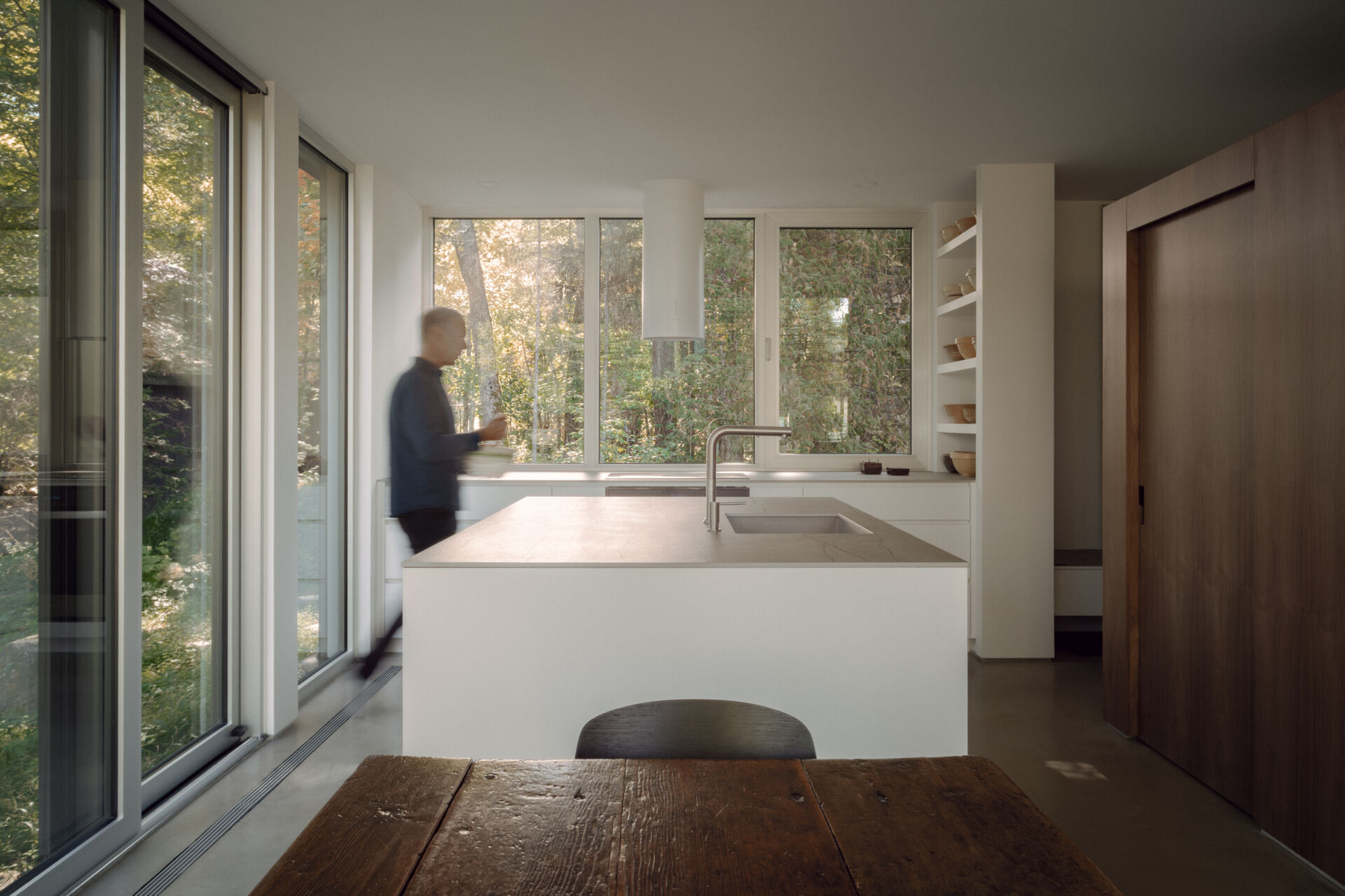 See how the dining room and kitchen are arranged around open views of the lake and forest in this contemporary Laurentians chalet by Appareil Architecture.
