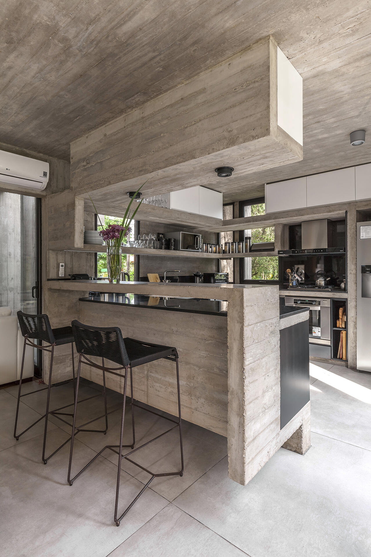 The Casa Aranzazu kitchen combines black cabinets and countertops with concrete shelving for a dark, modern material palette that complements the rest of the home.