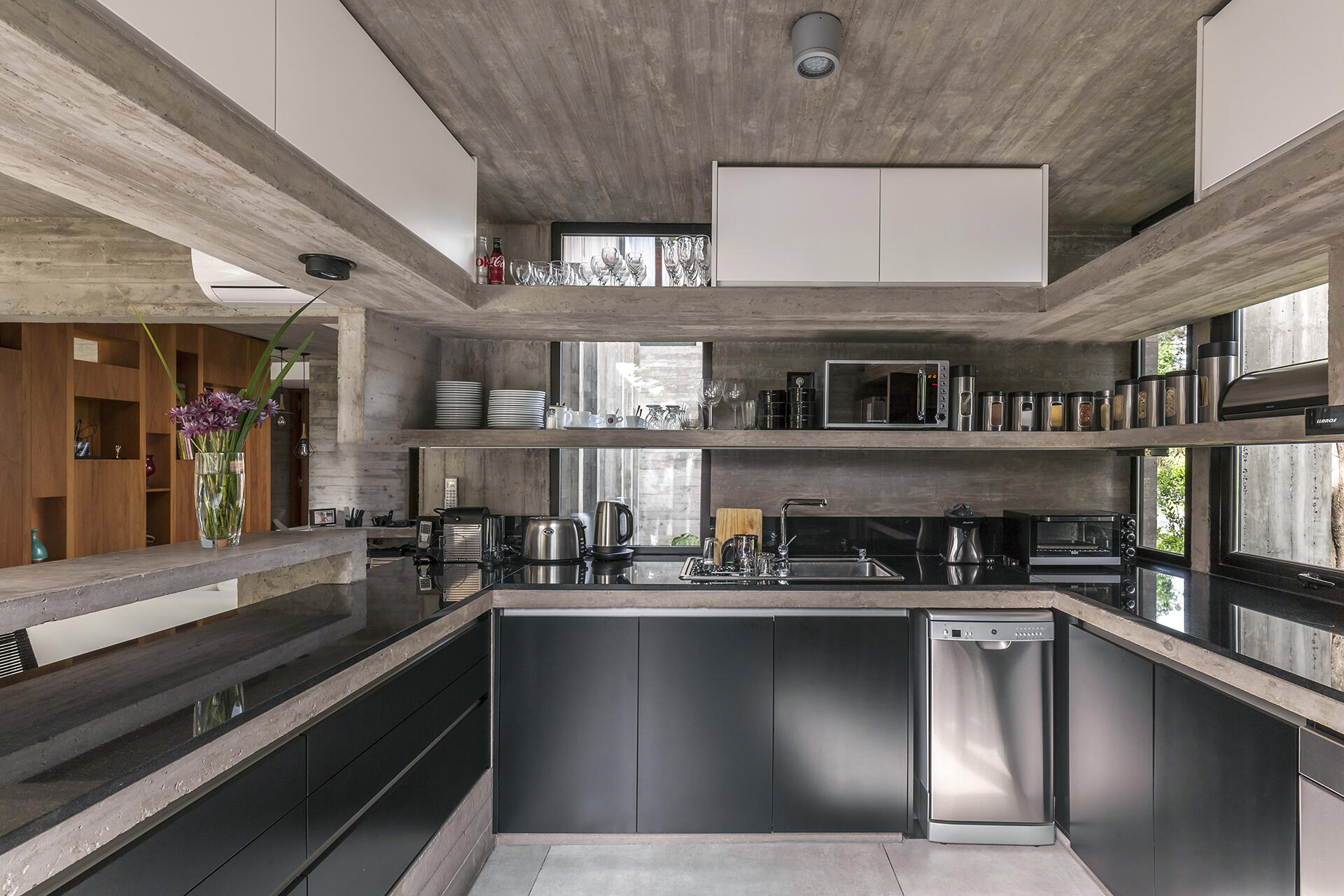 The Casa Aranzazu kitchen combines black cabinets and countertops with concrete shelving for a dark, modern material palette that complements the rest of the home.