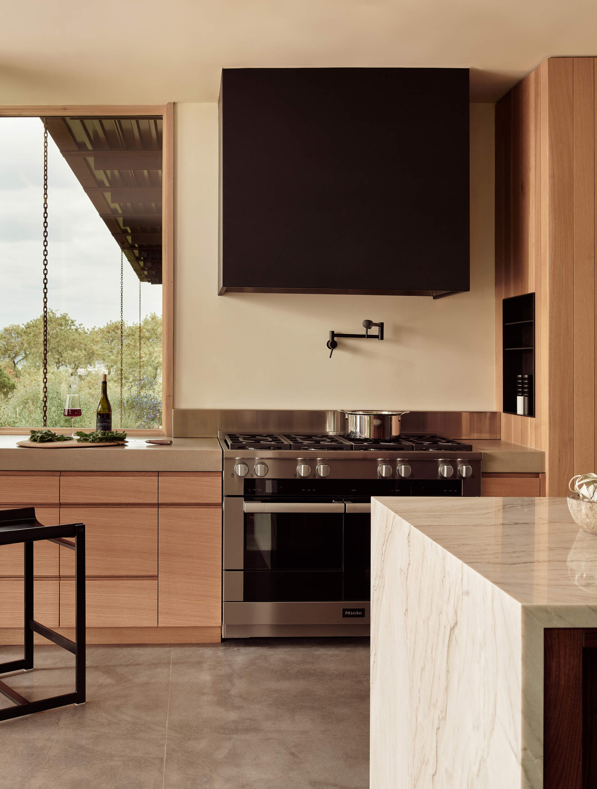 See how natural materials including white oak, walnut, slab stone and blackened steel come together in the central kitchen of Clayton Korte’s Vineyard Residence.