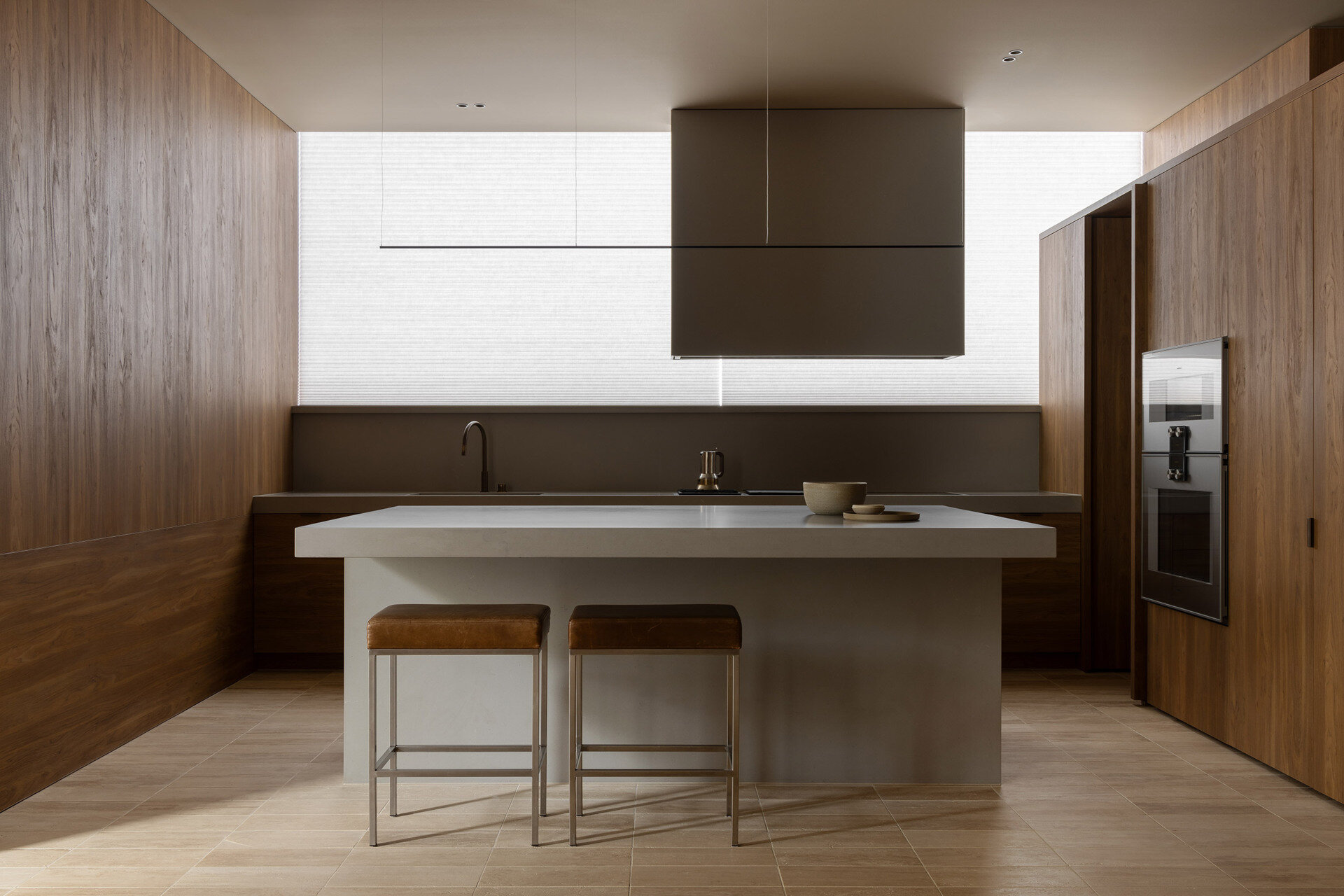 Casa Piva’s kitchen combines antique oak cabinetry, a pale island, leather stools and soft filtered light, creating one of the warmest and most tactile rooms in the house.