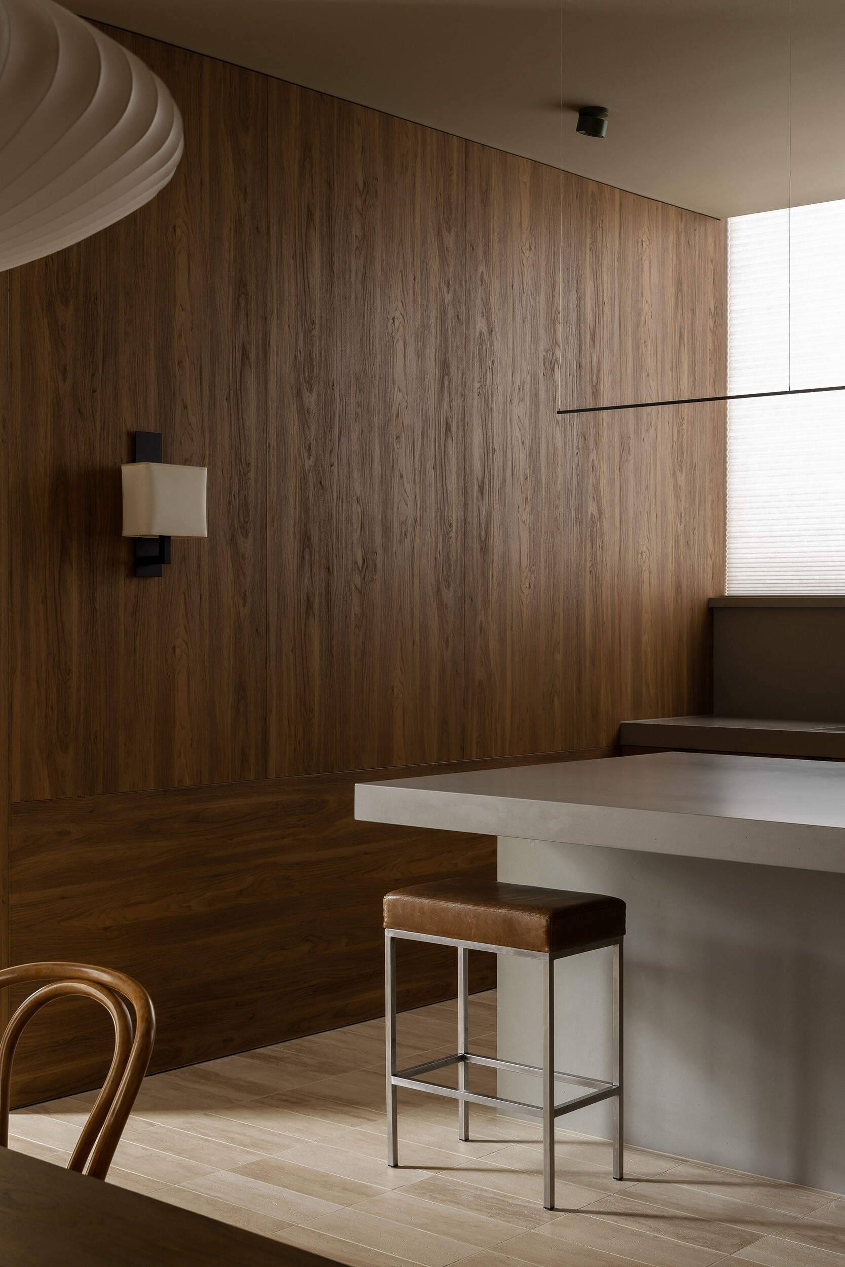 Casa Piva’s kitchen combines antique oak cabinetry, a pale island, leather stools and soft filtered light, creating one of the warmest and most tactile rooms in the house.