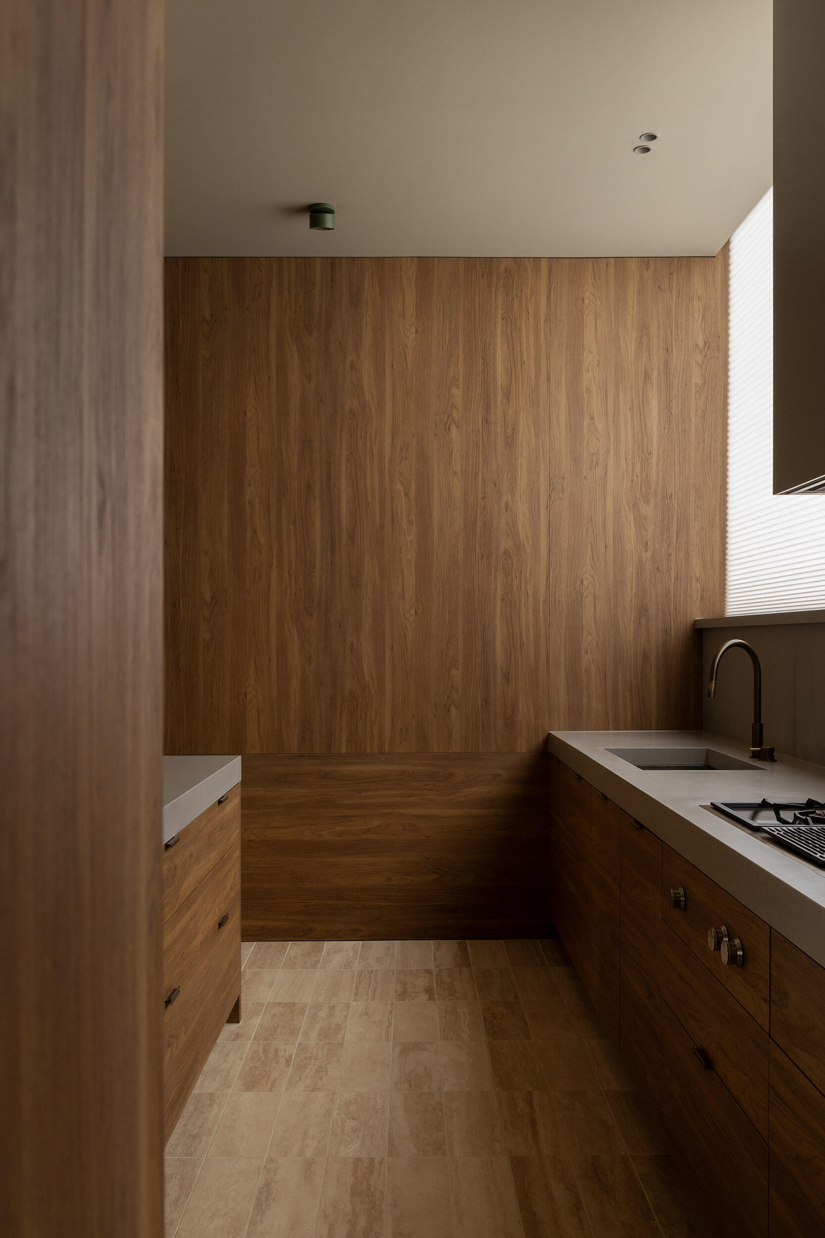 Casa Piva’s kitchen combines antique oak cabinetry, a pale island, leather stools and soft filtered light, creating one of the warmest and most tactile rooms in the house.