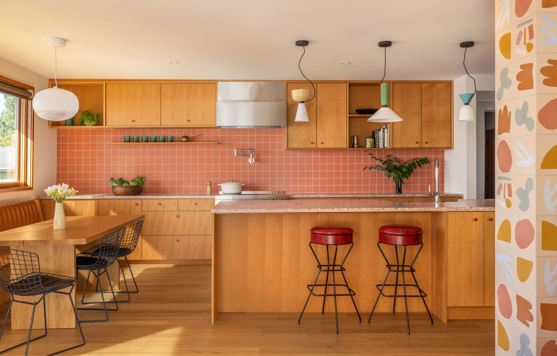 Tour the remodeled kitchen and dining area, where SHED flipped the original layout so a built-in banquette now faces Puget Sound, paired with warm timber cabinetry, pink Concrete Collaborative counters and a Zia Tile backsplash.