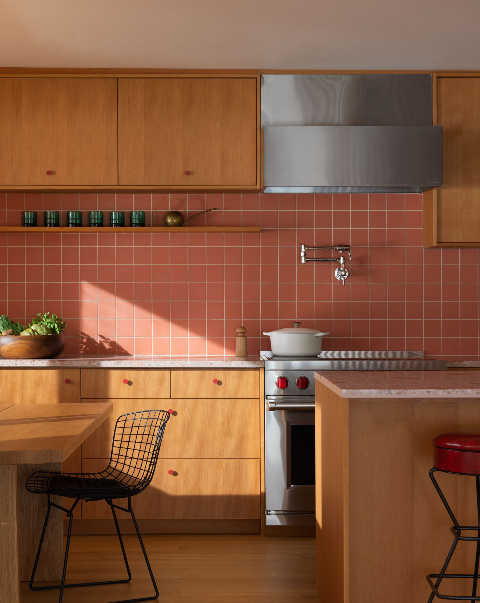 Tour the remodeled kitchen and dining area, where SHED flipped the original layout so a built-in banquette now faces Puget Sound, paired with warm timber cabinetry, pink Concrete Collaborative counters and a Zia Tile backsplash.