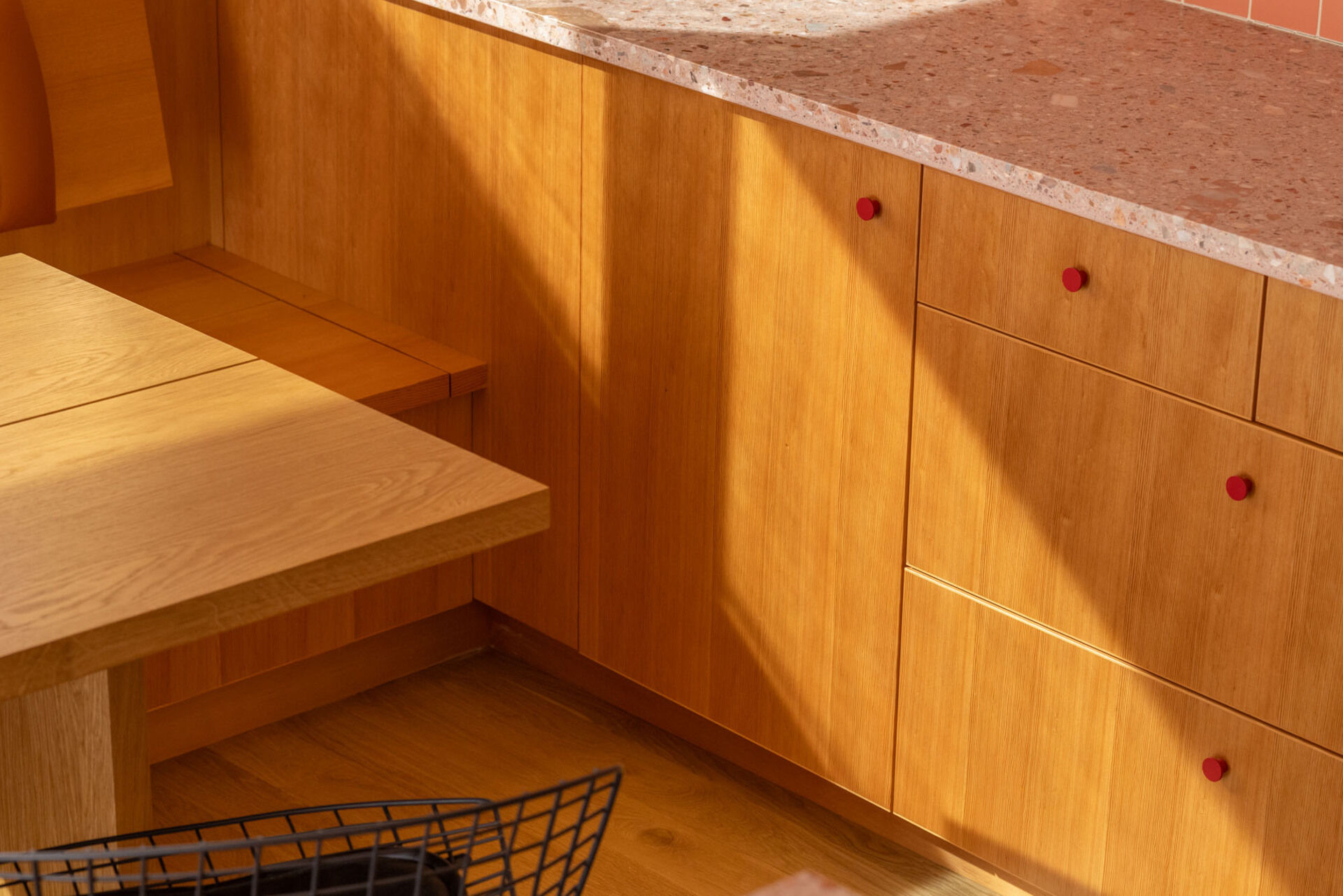 Tour the remodeled kitchen and dining area, where SHED flipped the original layout so a built-in banquette now faces Puget Sound, paired with warm timber cabinetry, pink Concrete Collaborative counters and a Zia Tile backsplash.