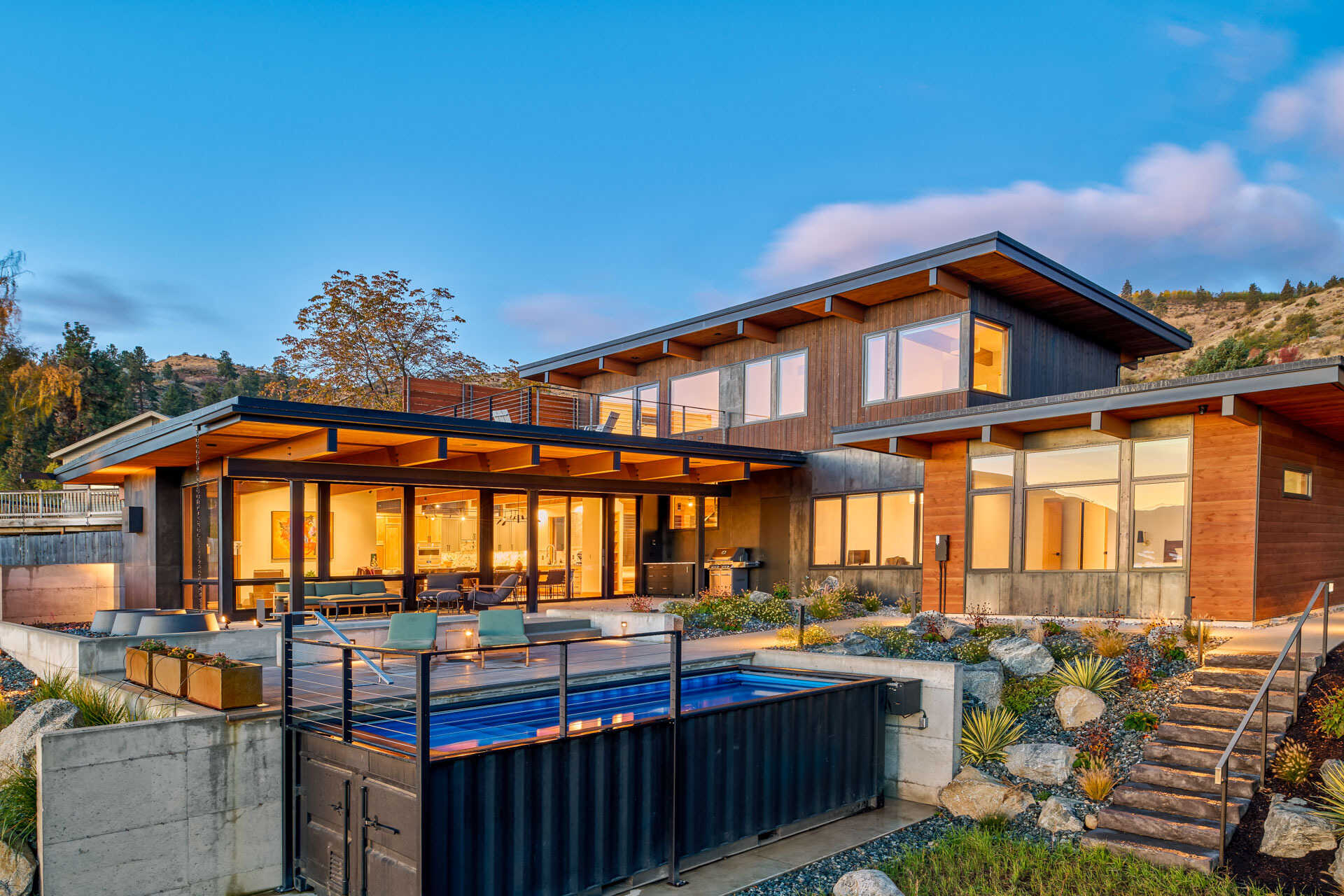 An L-shaped modern residence frames the surrounding landscape, creating a protected courtyard, pool terrace, and open views toward the lake and vineyard.