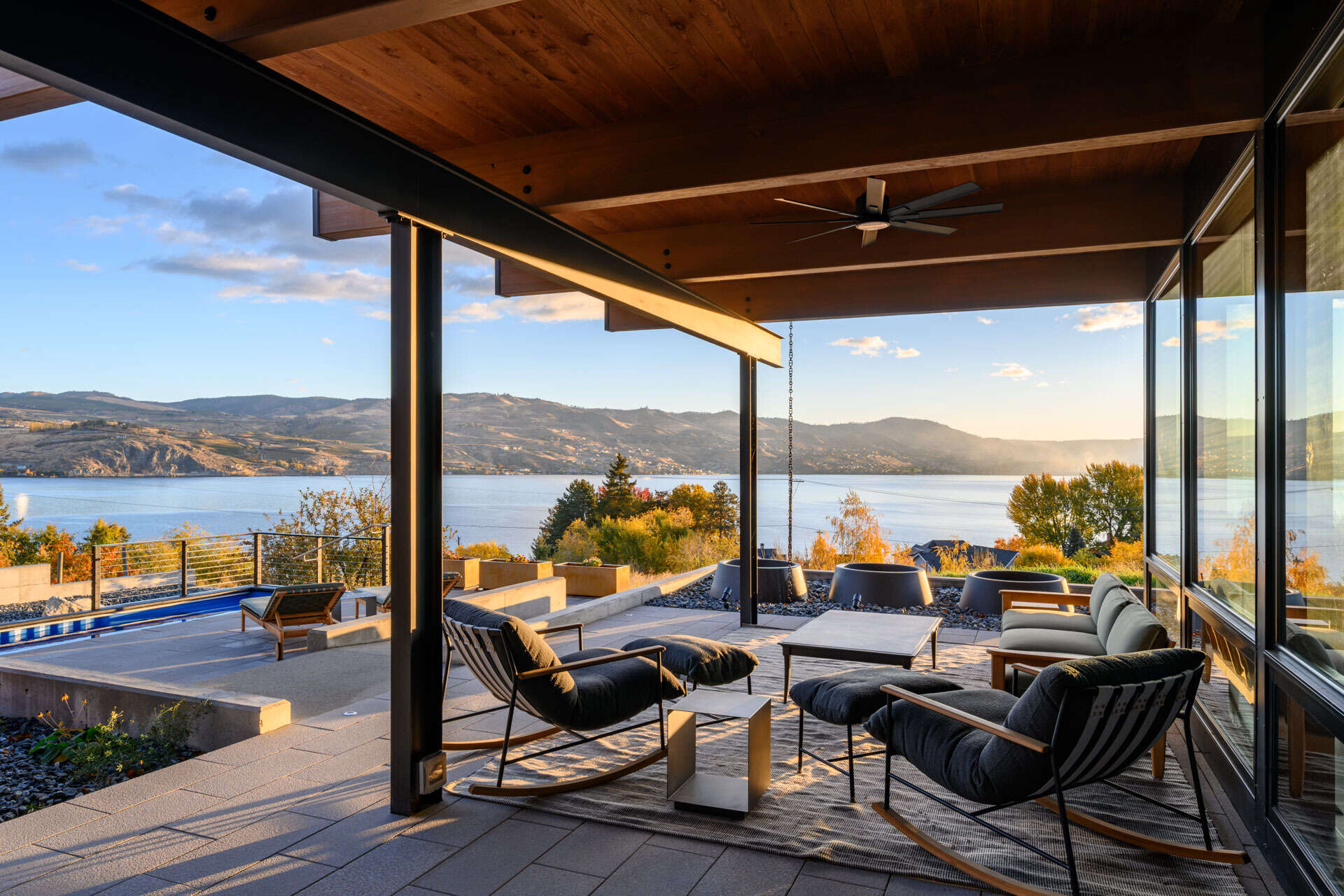 A repurposed shipping container pool anchors an outdoor living space, surrounded by a protected courtyard, covered patio, and views across the landscape.