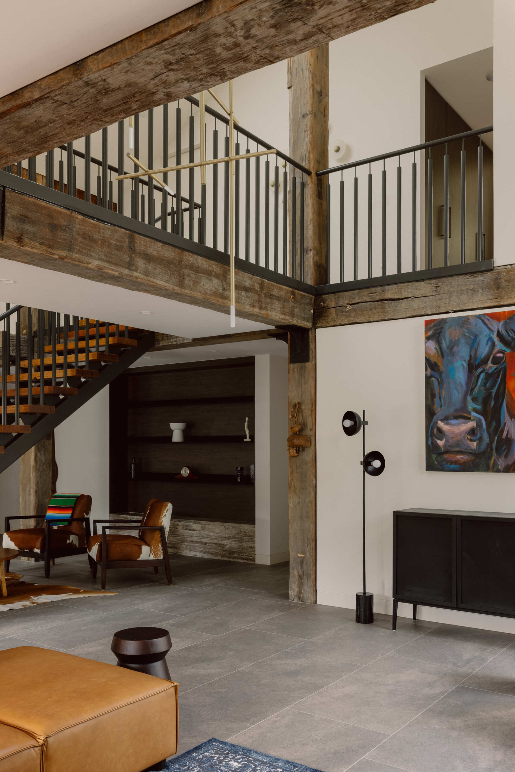 Step inside the living room of Yarra Valley House, featuring a large sectional, dark brick, exposed timber beams, grey flooring and expansive views.