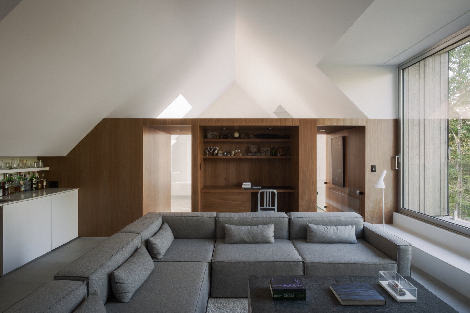 The upper-level living room at Chalet Moraine extends from the primary suite, with large dormers and deep-set glazing bringing views of the Laurentians landscape inside.