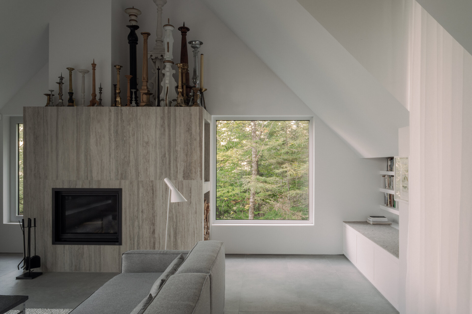 The upper-level living room at Chalet Moraine extends from the primary suite, with large dormers and deep-set glazing bringing views of the Laurentians landscape inside.