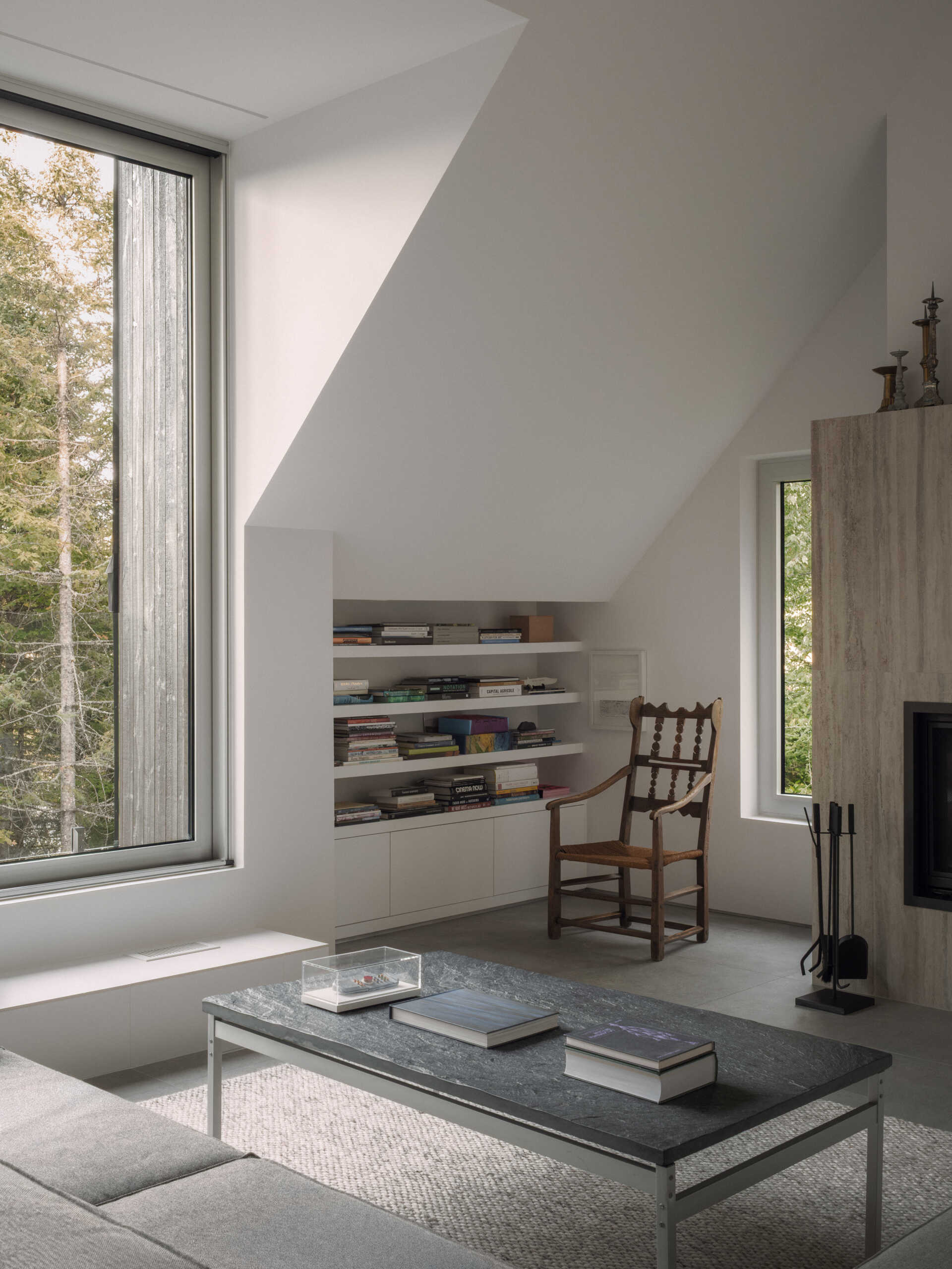 The upper-level living room at Chalet Moraine extends from the primary suite, with large dormers and deep-set glazing bringing views of the Laurentians landscape inside.