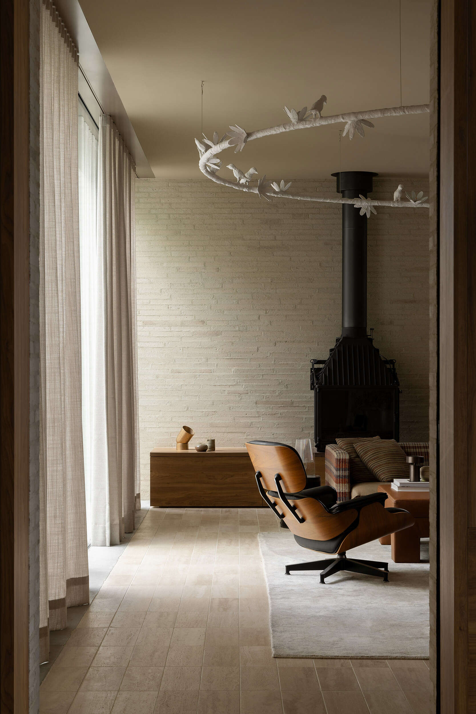 Casa Piva’s living room layers brick, timber and travertine with collected art, custom Perspex tables, an oversized plaster bird light and a sofa upholstered in vintage Missoni fabric.
