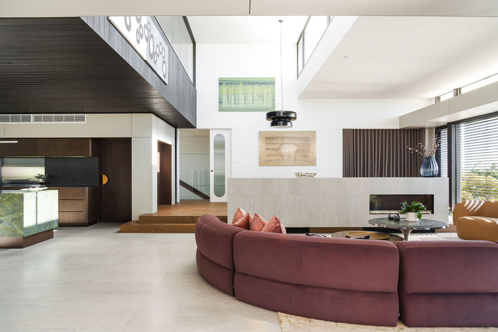 A curved couch and fireplace feature in the second living room at Mezzanine House, creating a relaxed space within the flexible Perth family home.