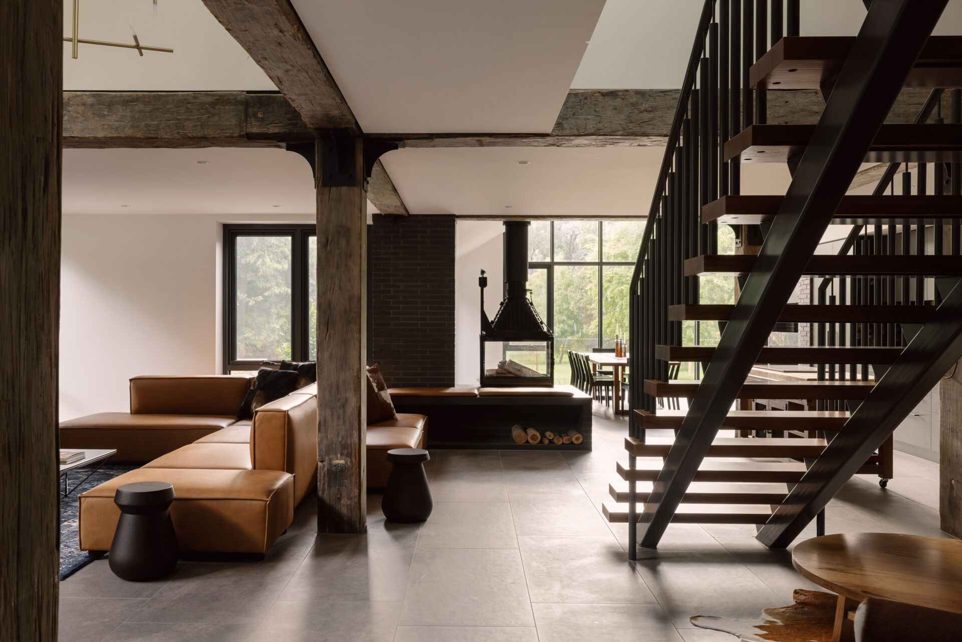 See the dramatic fireplace and reclaimed timber beams inside Yarra Valley House, where dark masonry and natural timber create a warm contemporary living space.