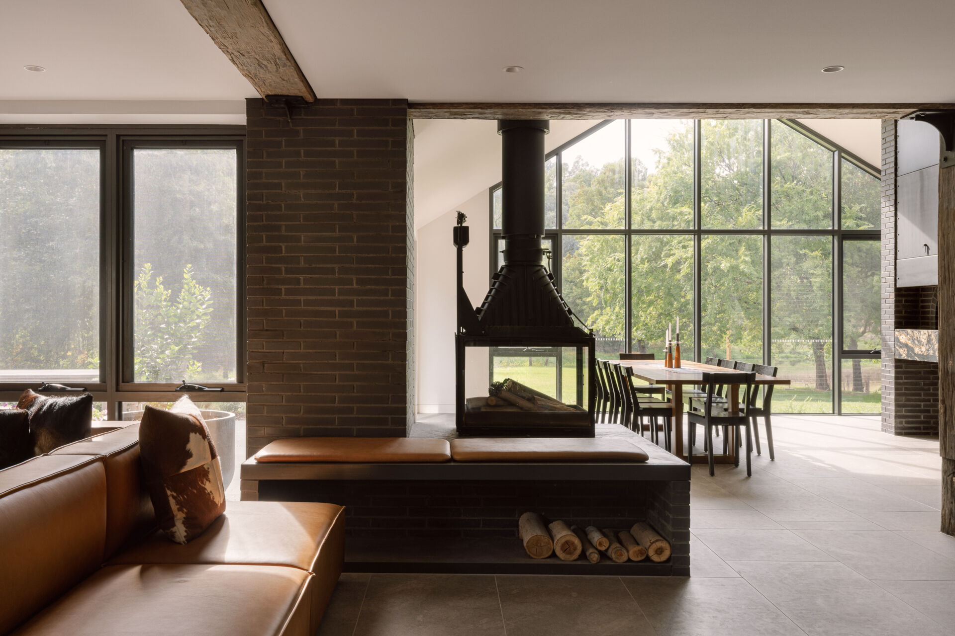 See the dramatic fireplace and reclaimed timber beams inside Yarra Valley House, where dark masonry and natural timber create a warm contemporary living space.