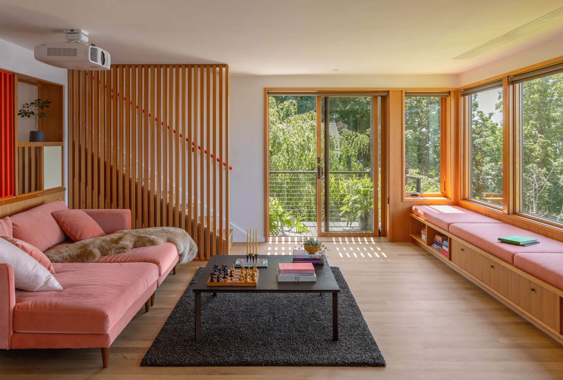 Step inside the renovated living room at Alki Lookout, where pale timber, pink upholstery, patterned tile and a long built-in window bench create a warm place to sit and watch ferries cross Puget Sound.