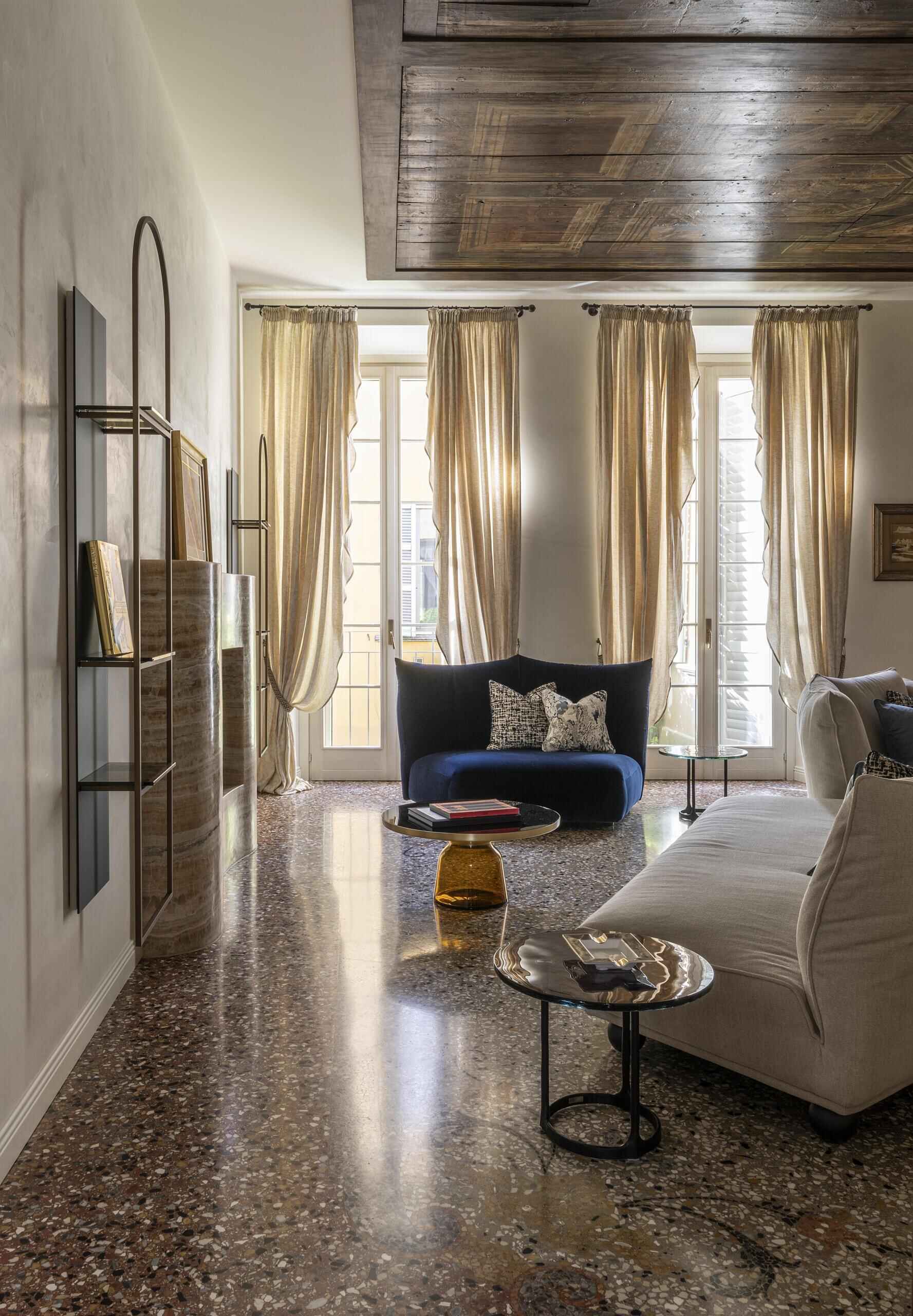 A sculptural onyx fireplace becomes the centrepiece of this Italian palazzo living room, paired with a large double-sided sofa, brass details and Venetian terrazzo.