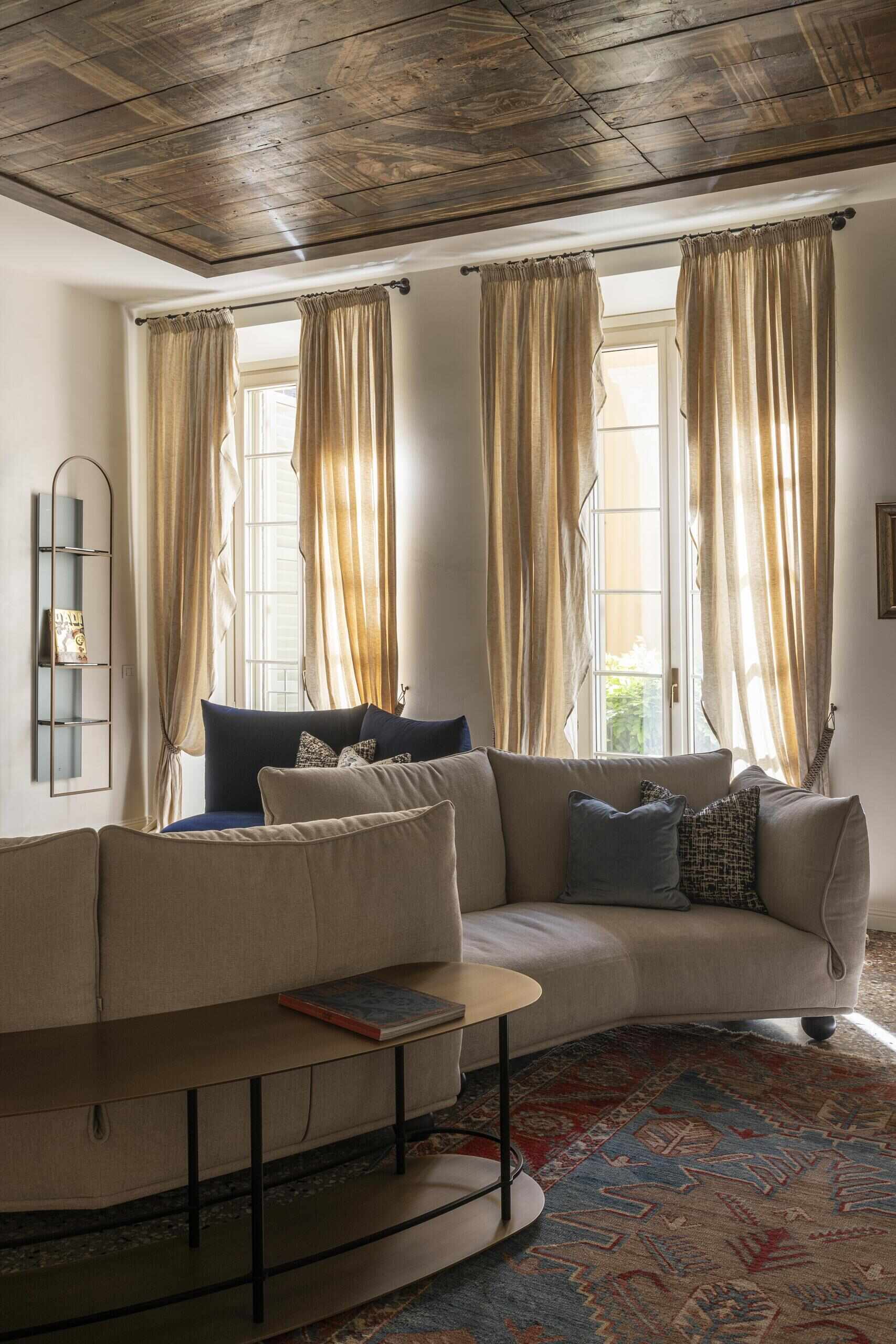 A sculptural onyx fireplace becomes the centrepiece of this Italian palazzo living room, paired with a large double-sided sofa, brass details and Venetian terrazzo.