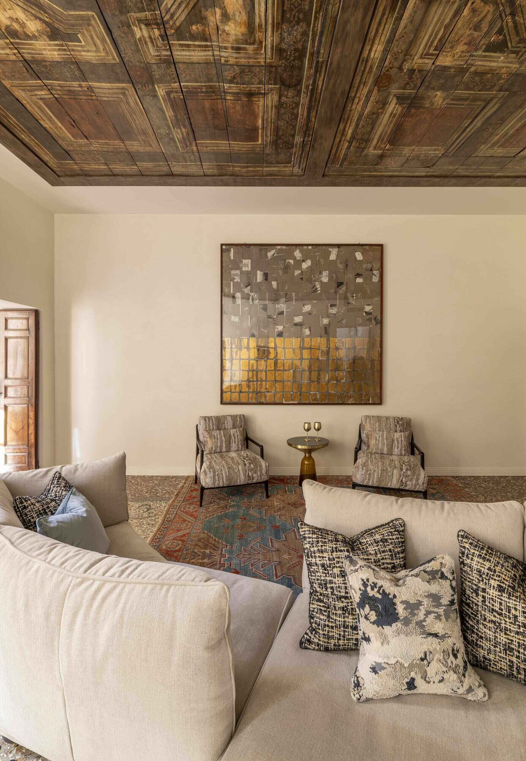 A sculptural onyx fireplace becomes the centrepiece of this Italian palazzo living room, paired with a large double-sided sofa, brass details and Venetian terrazzo.