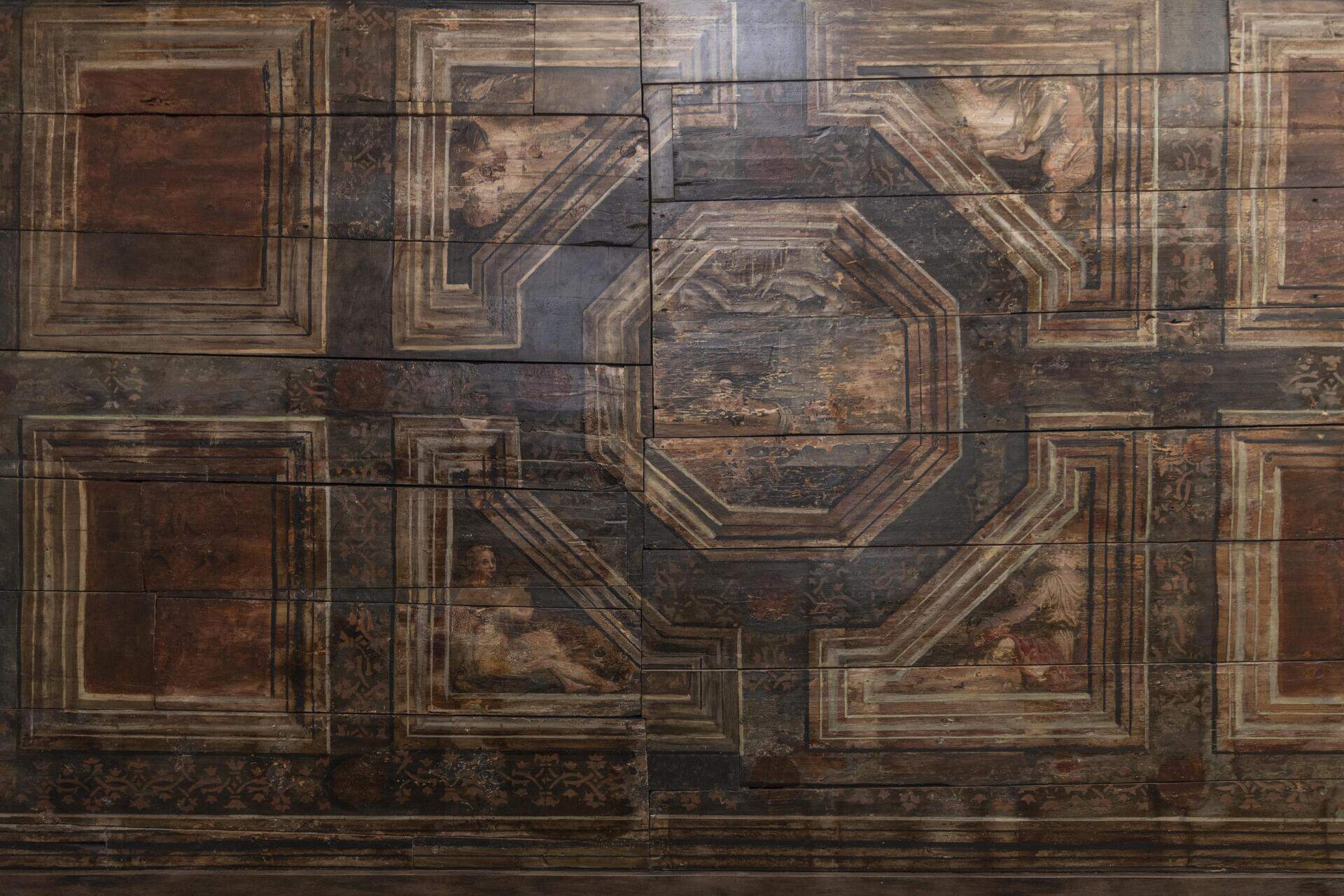ook inside a historic Italian palazzo living room with a sumptuous decorated ceiling featuring restored 17th-century church portals alongside contemporary interiors.