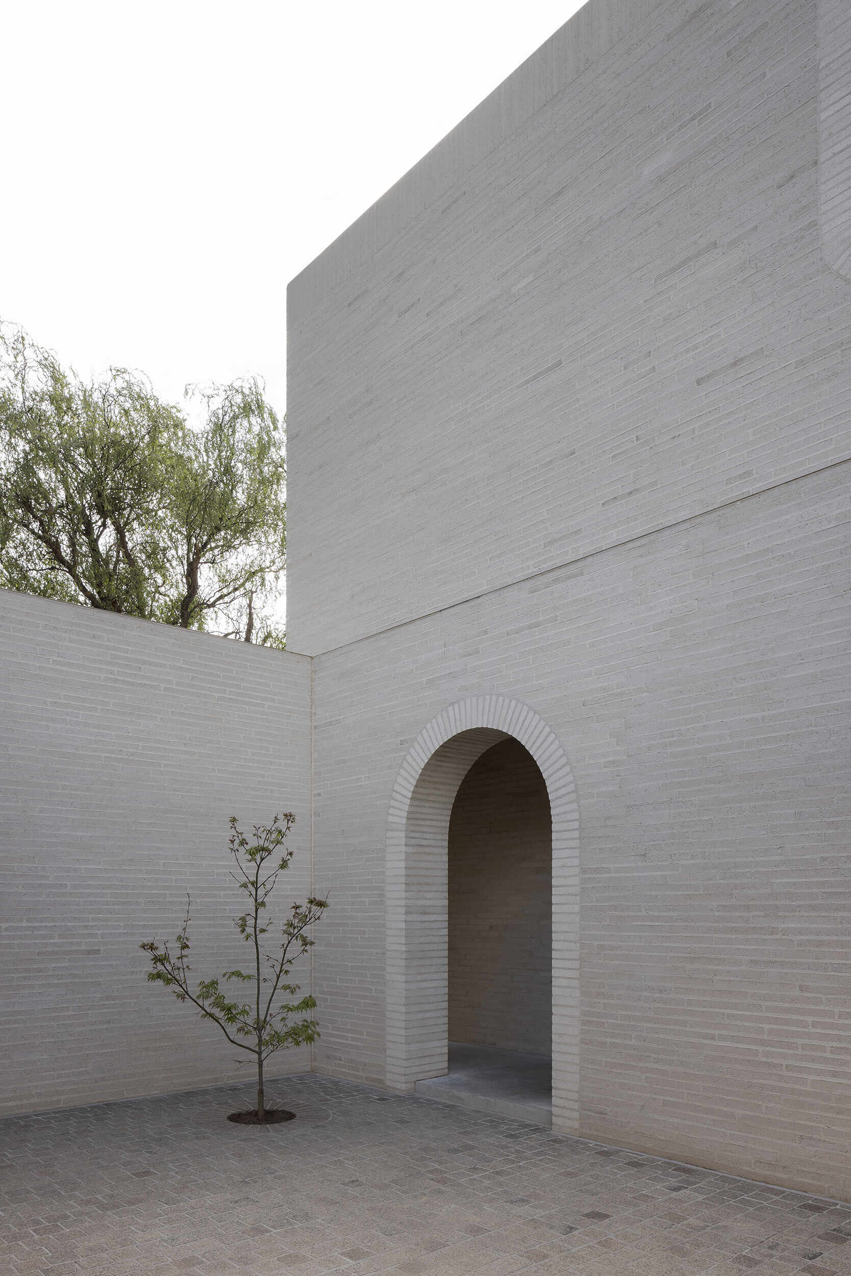 A single arch leads into Casa Piva’s low-lit entry sequence, passing the service and secondary rooms before the house begins to open towards the warmer kitchen and living areas.