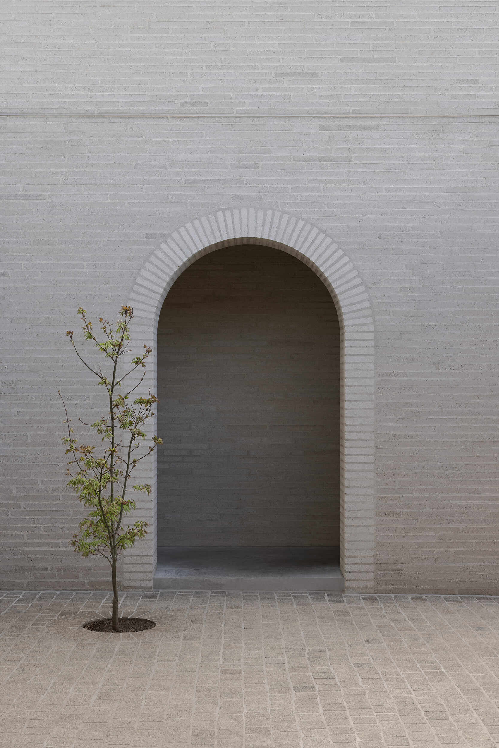 A single arch leads into Casa Piva’s low-lit entry sequence, passing the service and secondary rooms before the house begins to open towards the warmer kitchen and living areas.