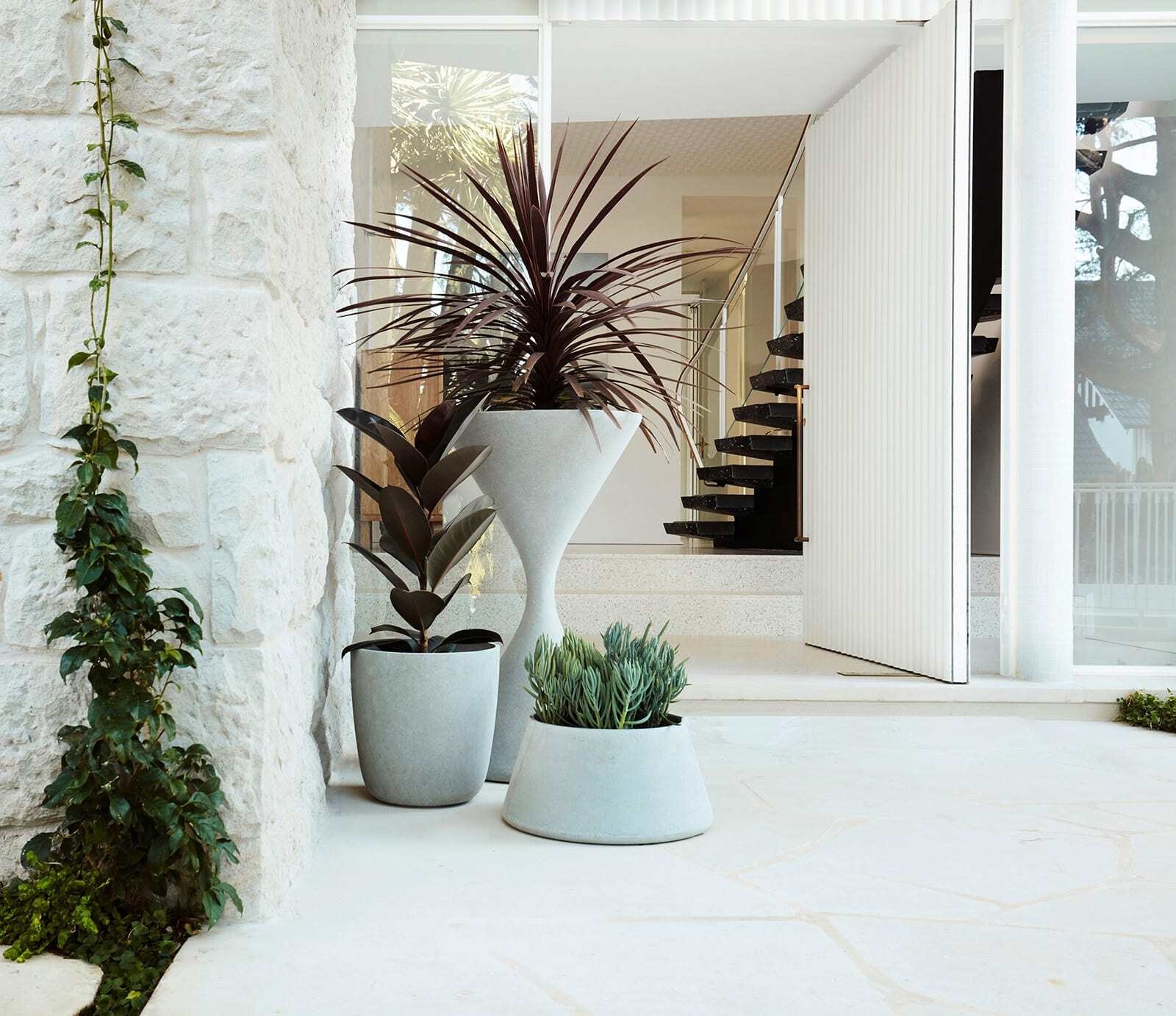 A sculptural curved concrete awning inspired by Oscar Niemeyer welcomes visitors to this Bellevue Hill modernist home, paired with a large white pivot front door.