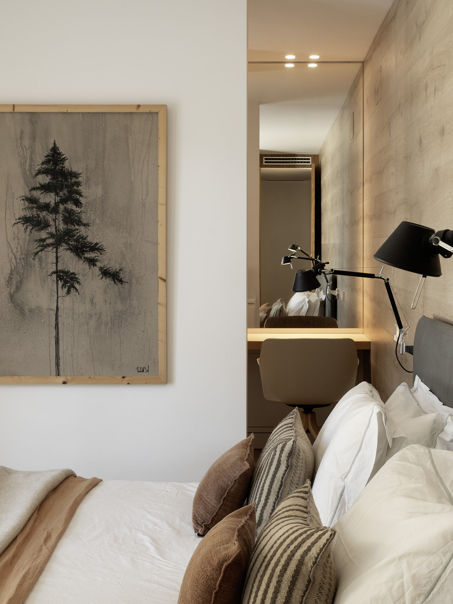The primary bedroom pairs a Gervasoni bed with warm timber cladding, neutral textiles and direct views toward the pool. The ensuite features twin vanity areas with stone basins, brass taps and timber-framed windows.