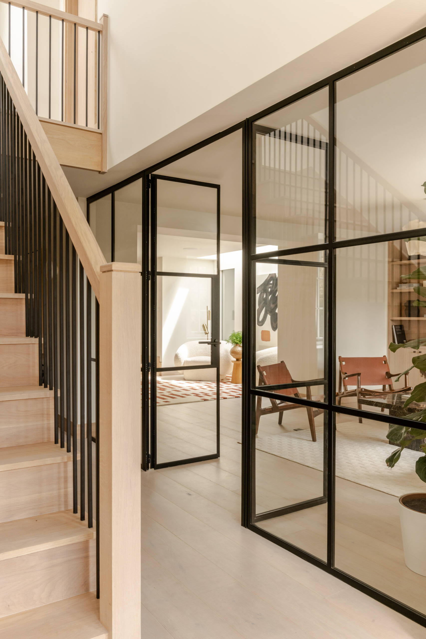 Explore the sitting room at Thirsk Cottage, where a black-framed glass wall, pale wood, warm leather and a dark fireplace create a comfortable balance of modern and natural materials.