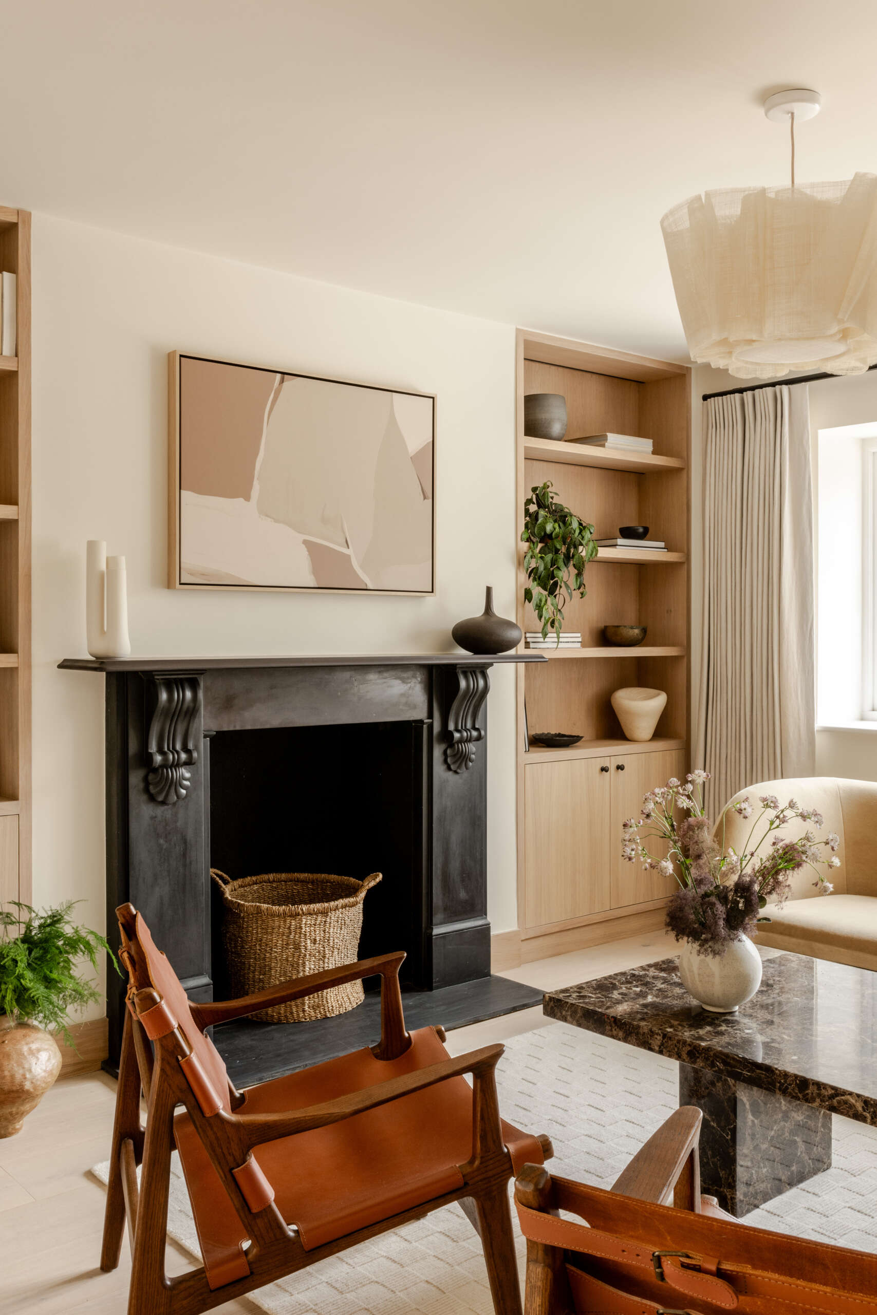 Explore the sitting room at Thirsk Cottage, where a black-framed glass wall, pale wood, warm leather and a dark fireplace create a comfortable balance of modern and natural materials.