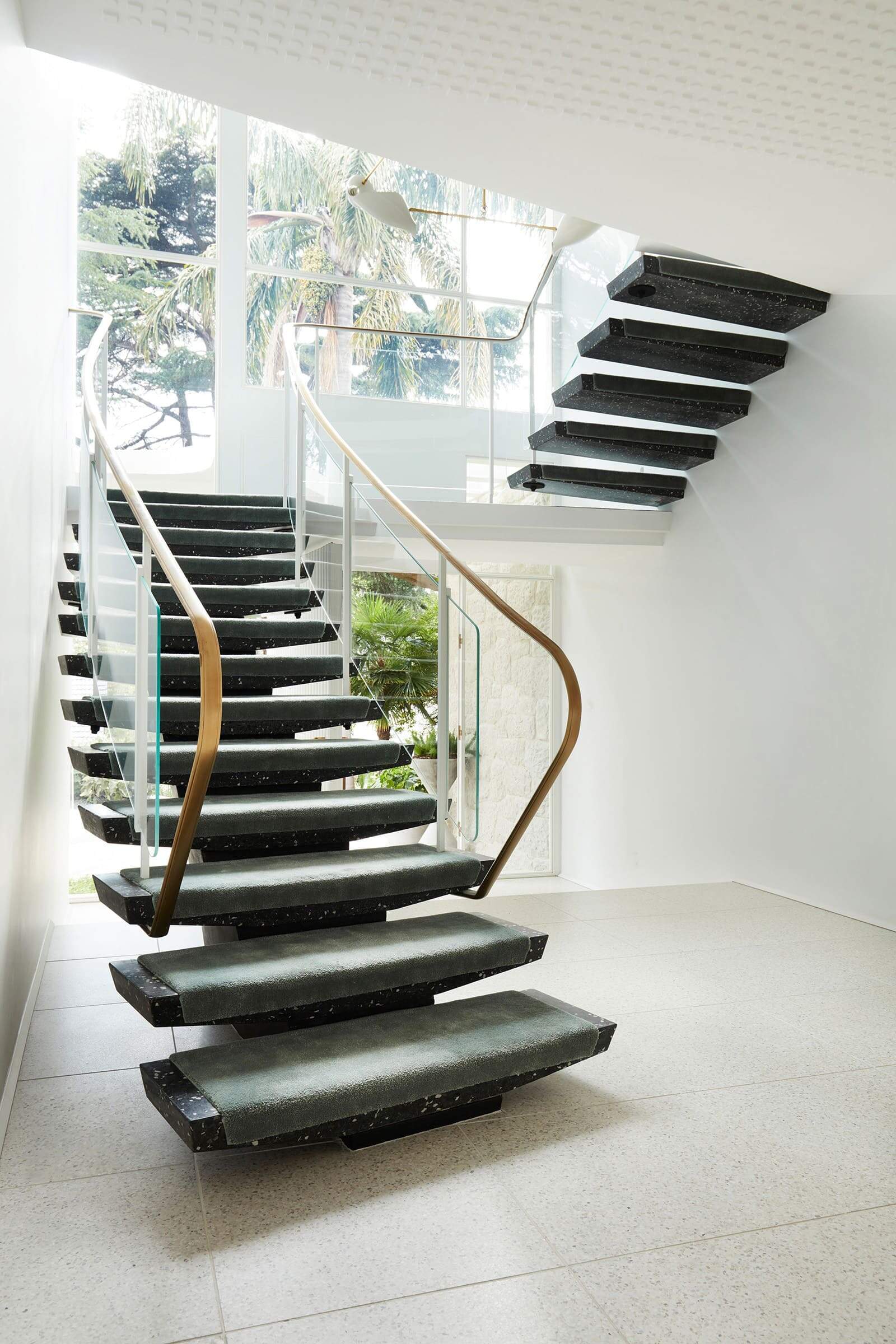The original George Reeves switchback staircase has been restored with a brass handrail and frameless glass balustrade, combining 1960s modernism with contemporary detailing.
