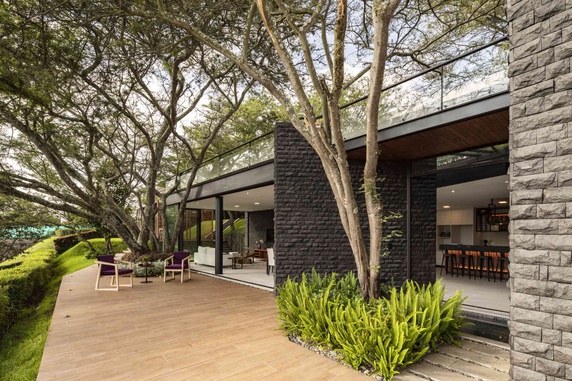 See how the Hidden Stone House uses its deck to create an outdoor space among mature trees, extending the home's relationship with nature.