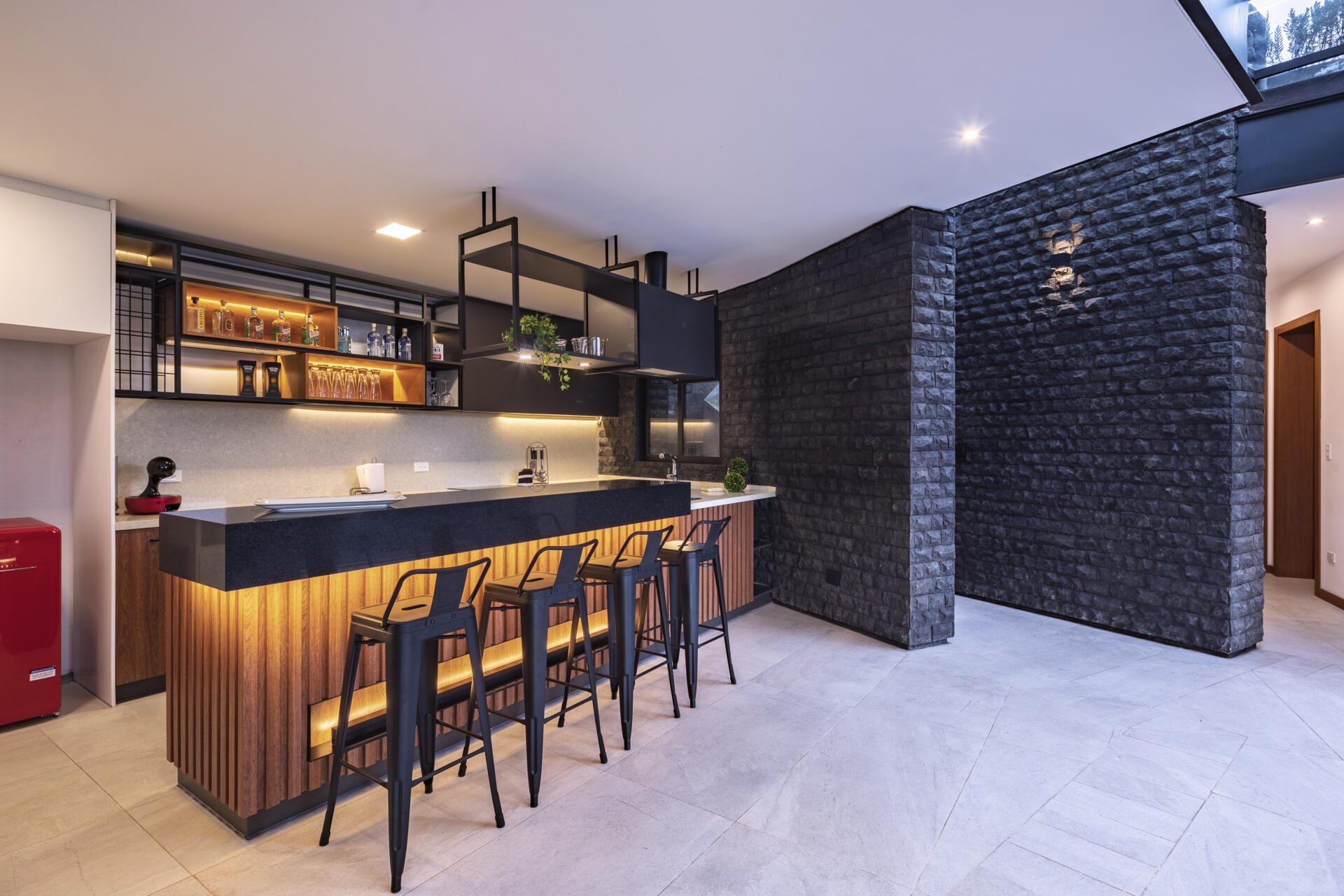 Take a look inside the Hidden Stone House kitchen, where warm wood slats, matte black cabinetry, dark stone and a generous island create a sophisticated modern interior.