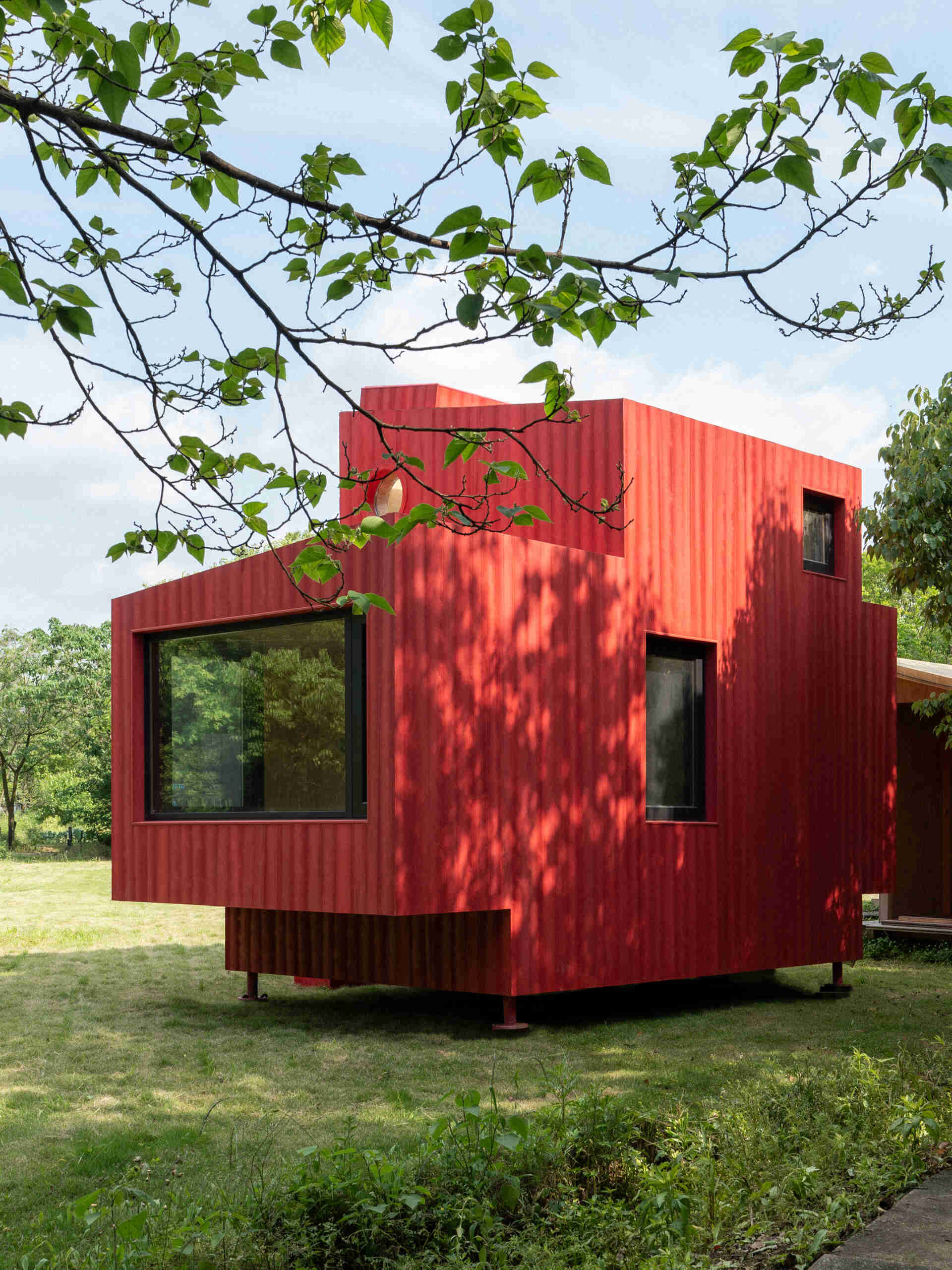 Wiki World’s Red Submarine Cabin brings the playful feeling of a submarine into the forest, with a vibrant red exterior, circular portholes and a compact timber interior.